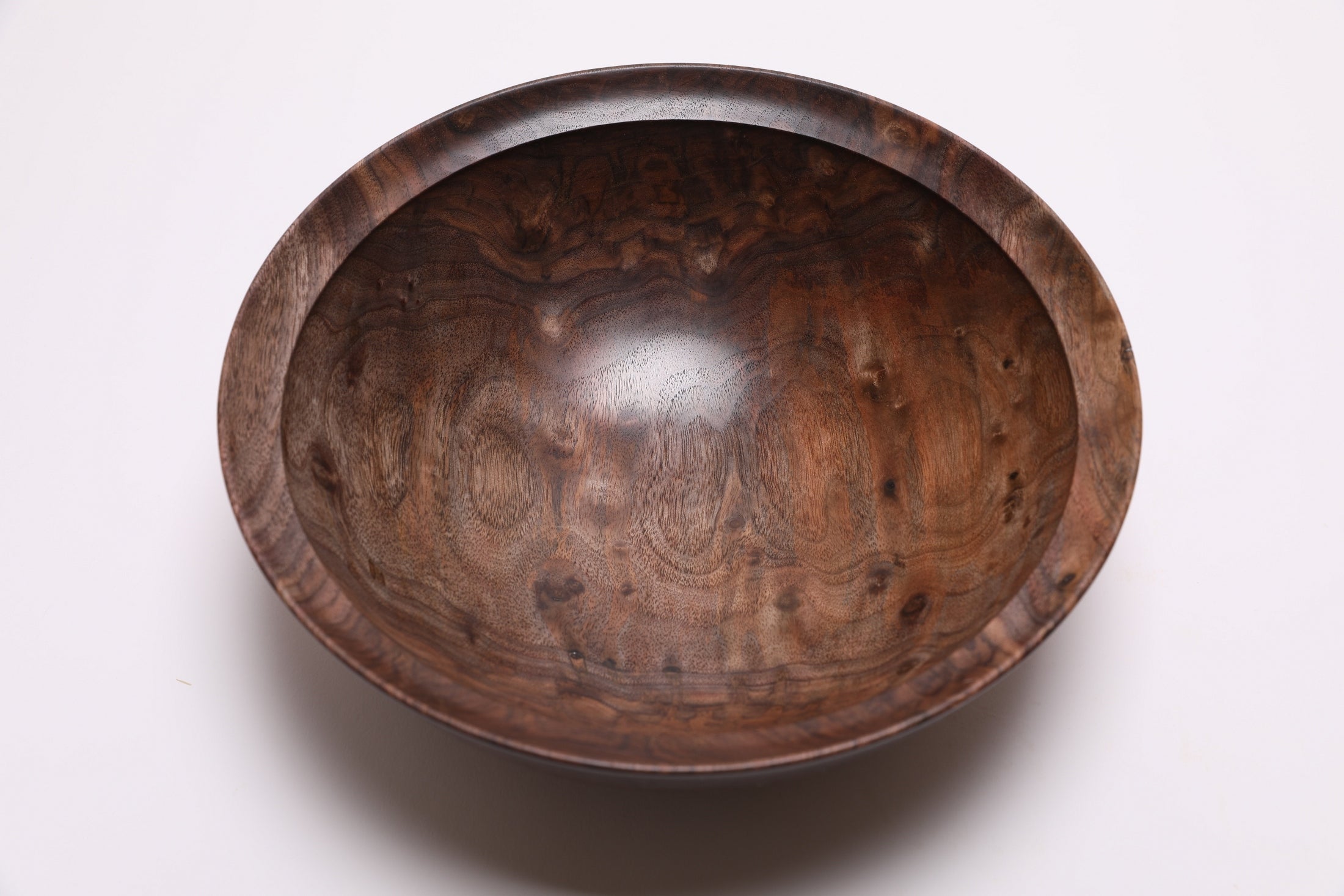 Handcrafted curly black walnut bowl side view displaying 3 1/2 inch depth and rounded curved taper