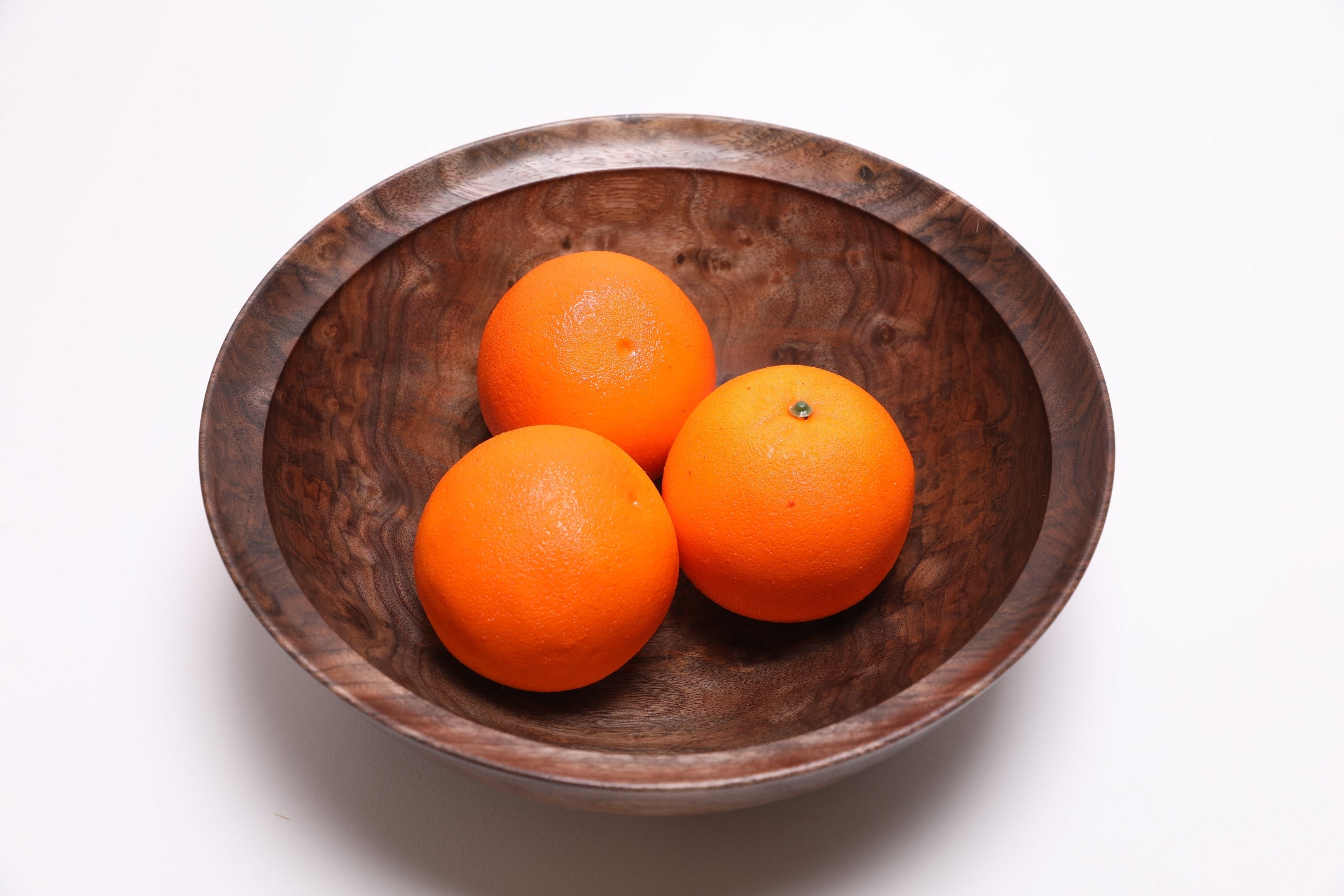Black walnut bowl with three oranges in it.  Curly grain detail showing amber and tan highlights and natural wood beauty