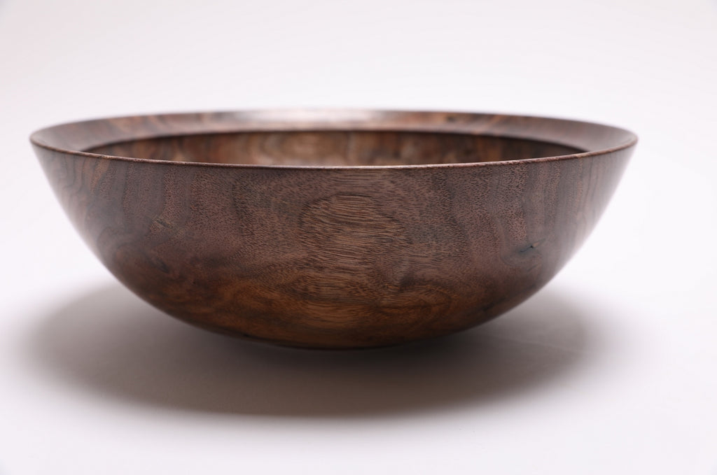 Handmade curly walnut bowl angle view displaying undercut rim and raised foot design