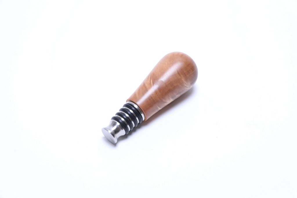 Big leaf maple burl wooden wine stopper top view highlighting quilted figure and amber tones
