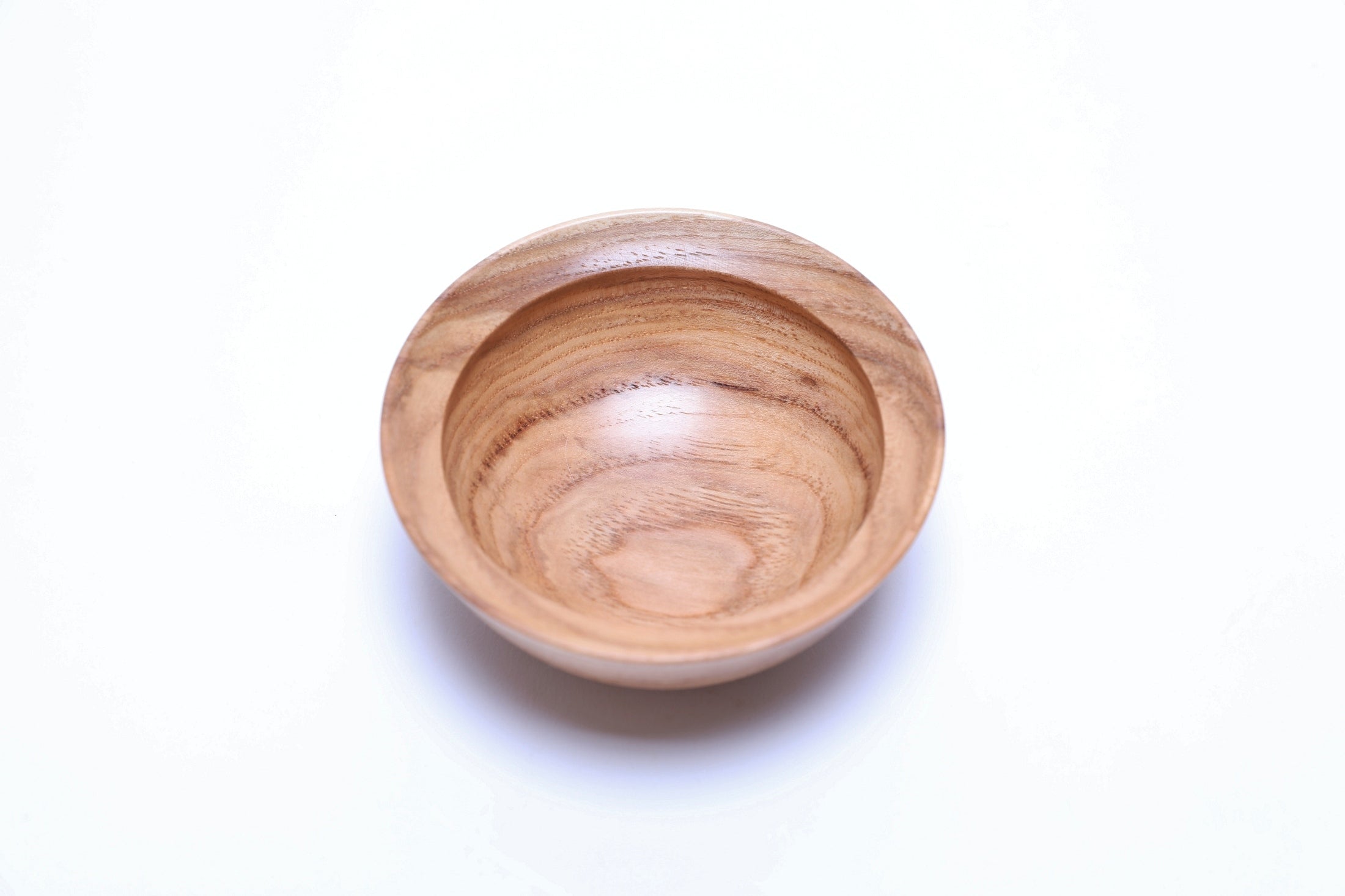 Small handcrafted hickory bowl with centered growth rings and amber transition lines, overhead view