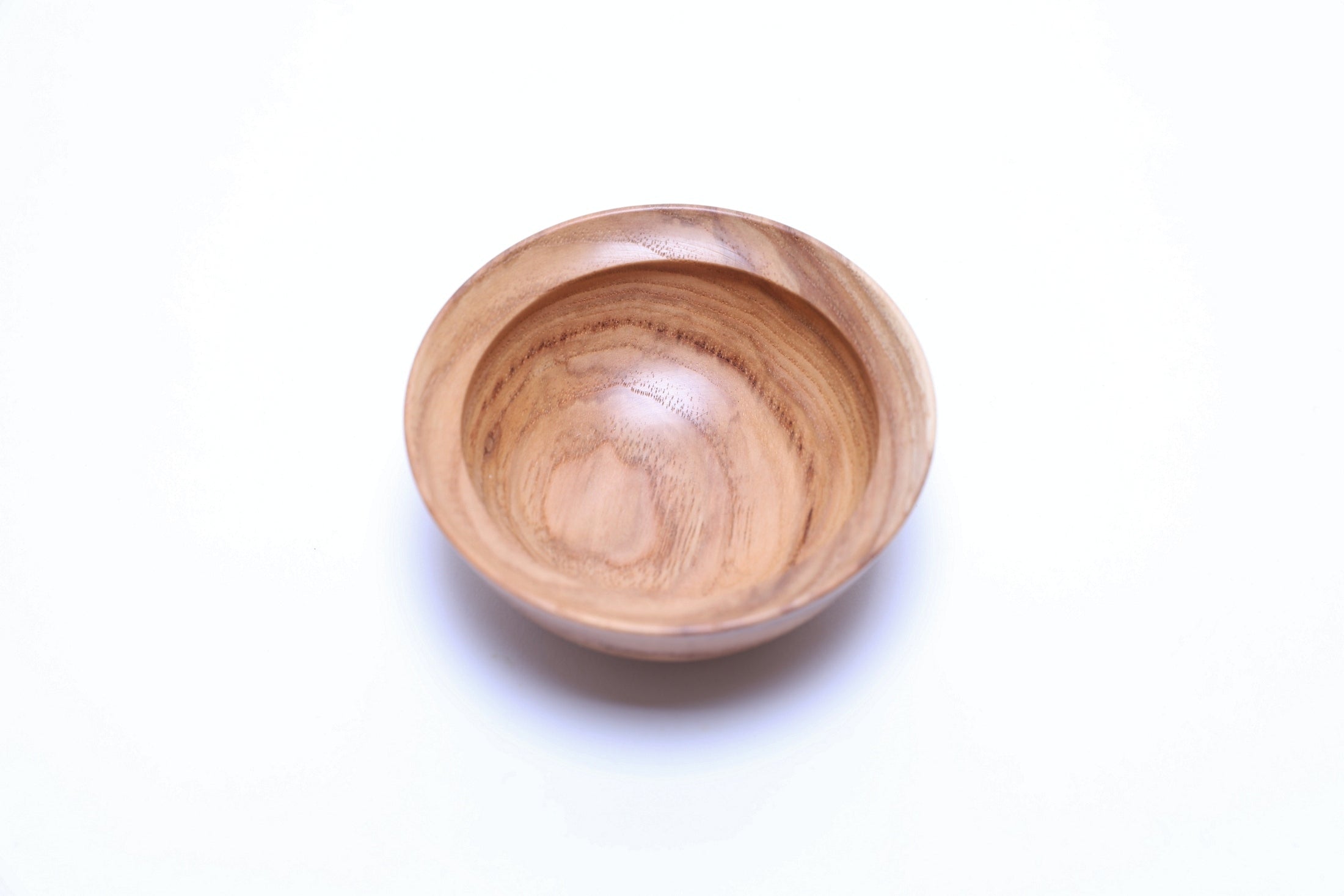 Very small hickory wood bowl showing natural grain pattern and curved taper rim, angled view