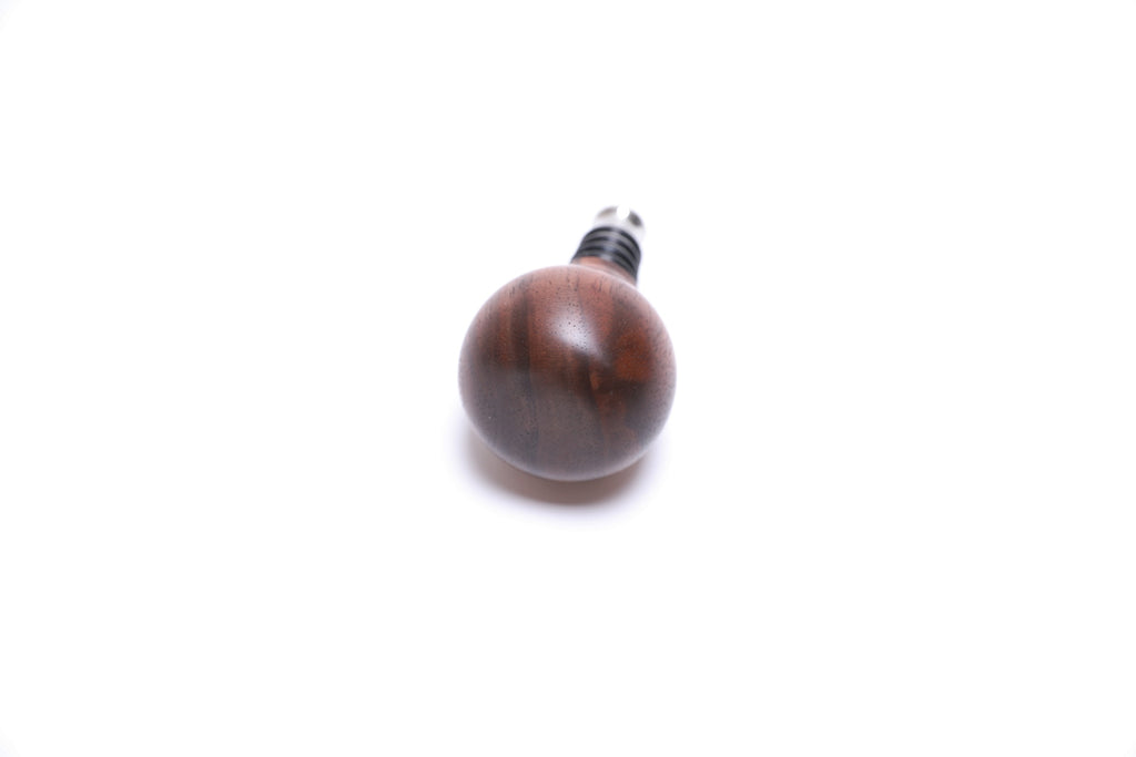 Walnut burl wooden wine stopper top view highlighting red highlights and burl pattern