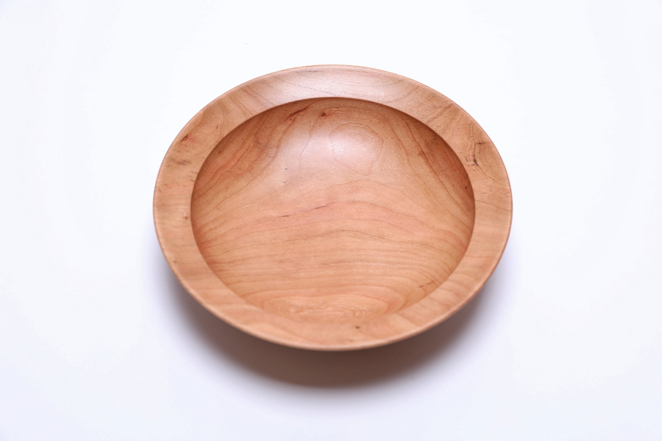 Small cherry wood bowl showing wavy growth ring transition lines, close-up