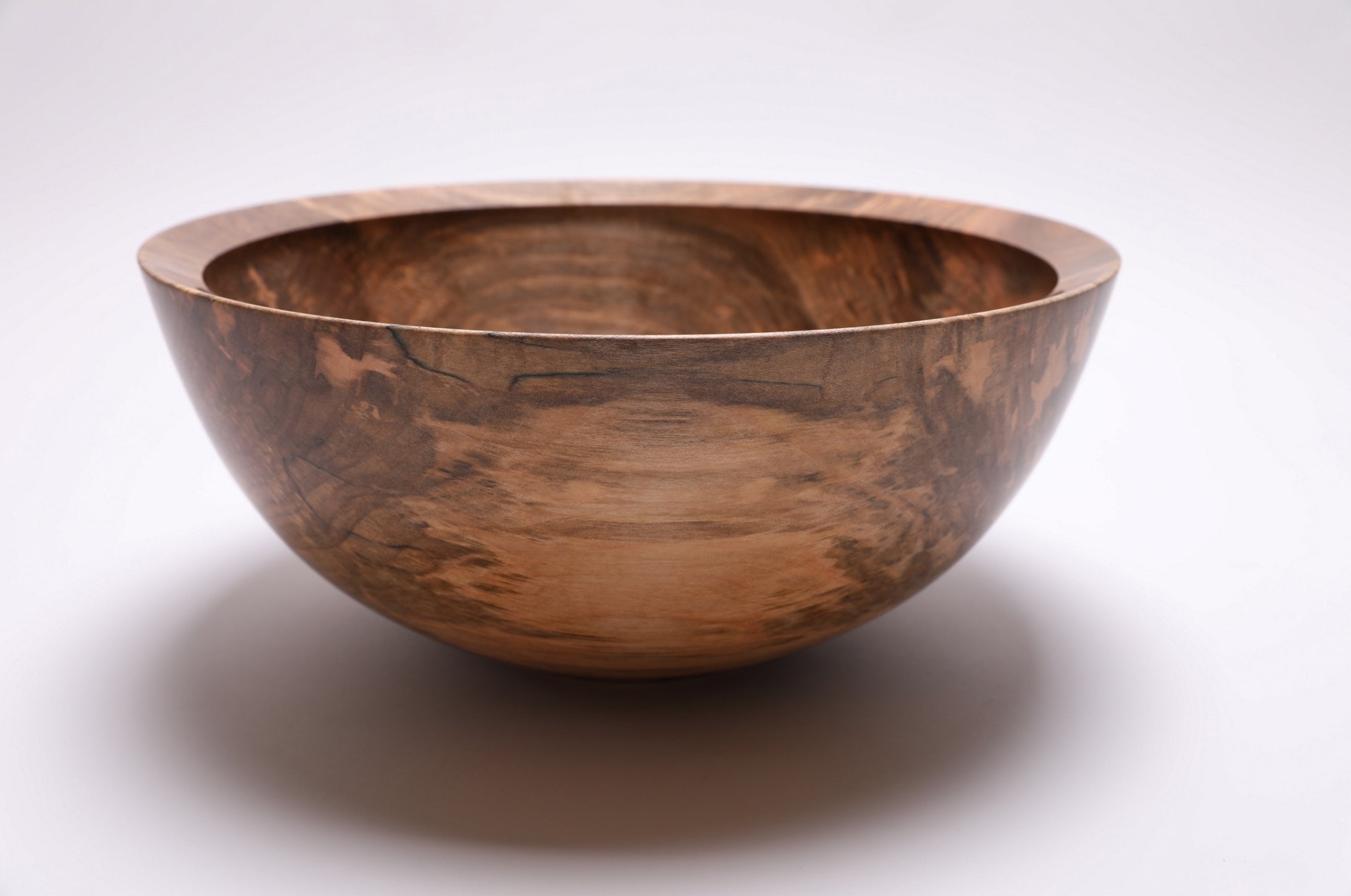 Side profile of large spalted maple salad bowl showing curved taper, undercut rim, and raised foot