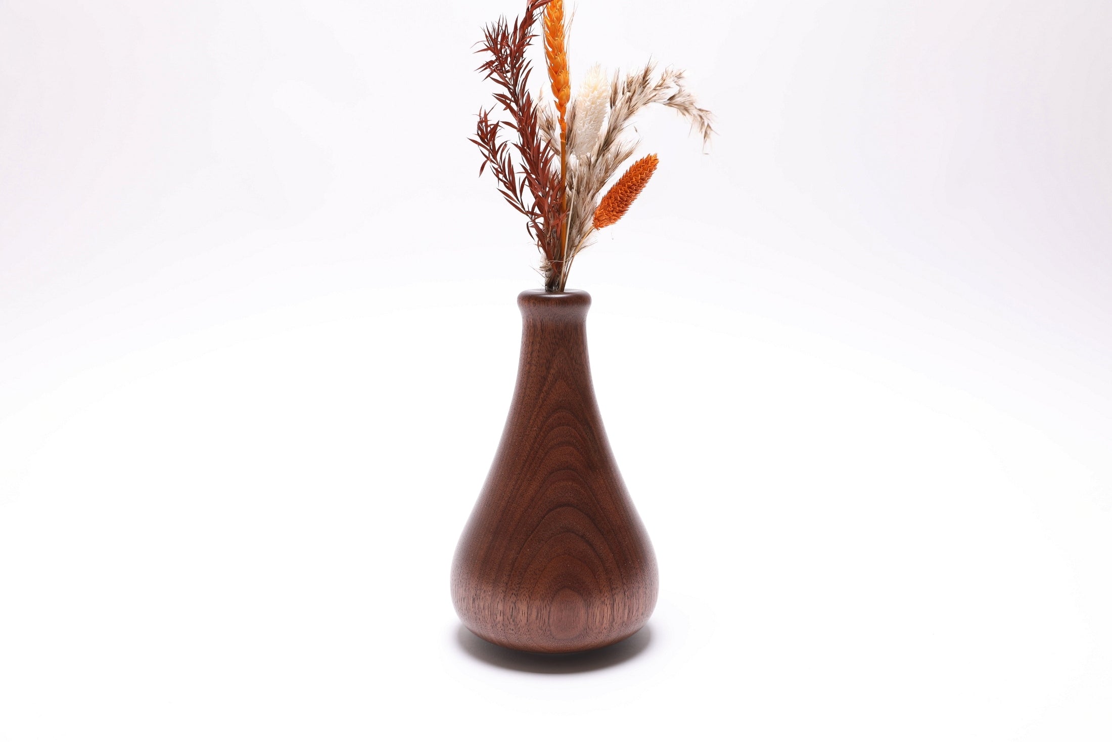 Quartersawn black walnut weed pot with vertical grain lines with dry flowers