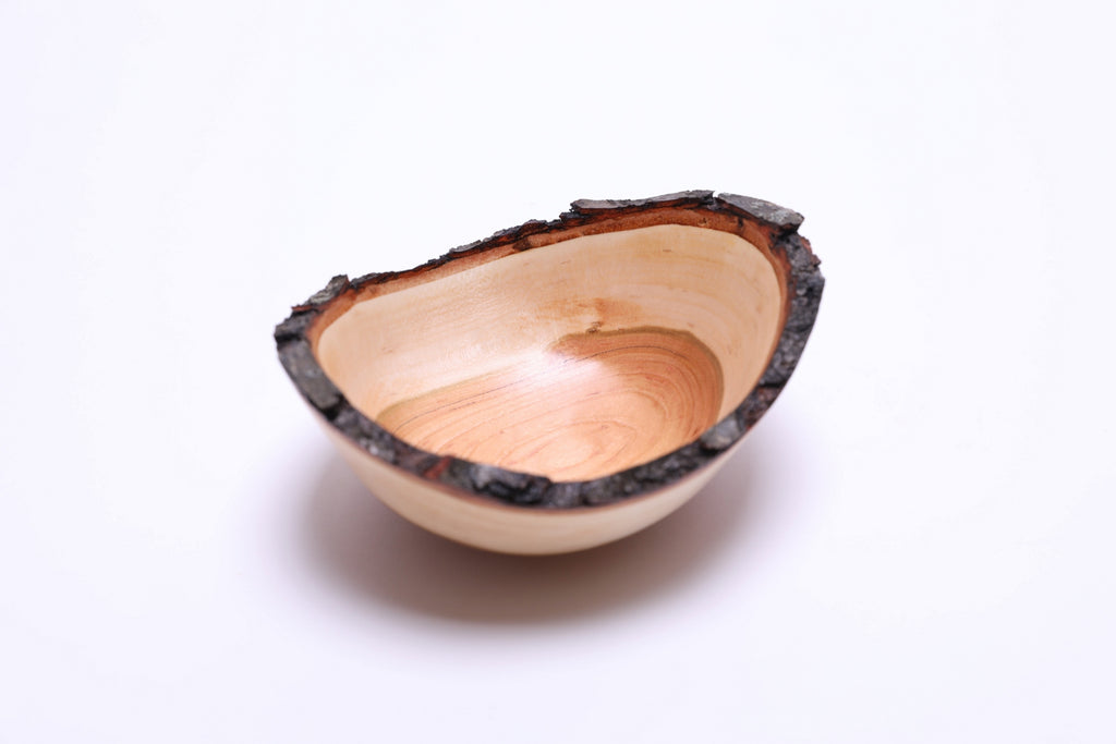 Handmade cherry wood bowl showing dark brown bark and reddish inner bark