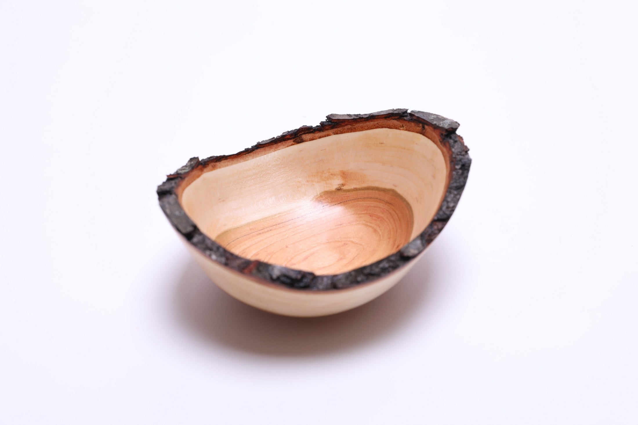 Handmade cherry wood bowl showing dark brown bark and reddish inner bark