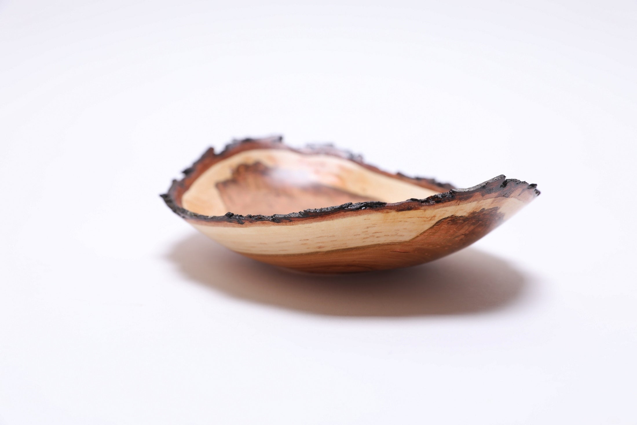 Natural edge wild black cherry bowl, side view at 180°, cream sapwood band and warm heartwood tones, Sanders Woodworking