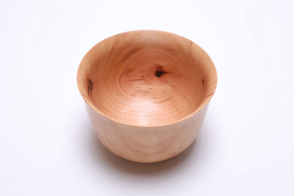 Angled view of pecan wood bowl highlighting sculptural rim and wood grain texture