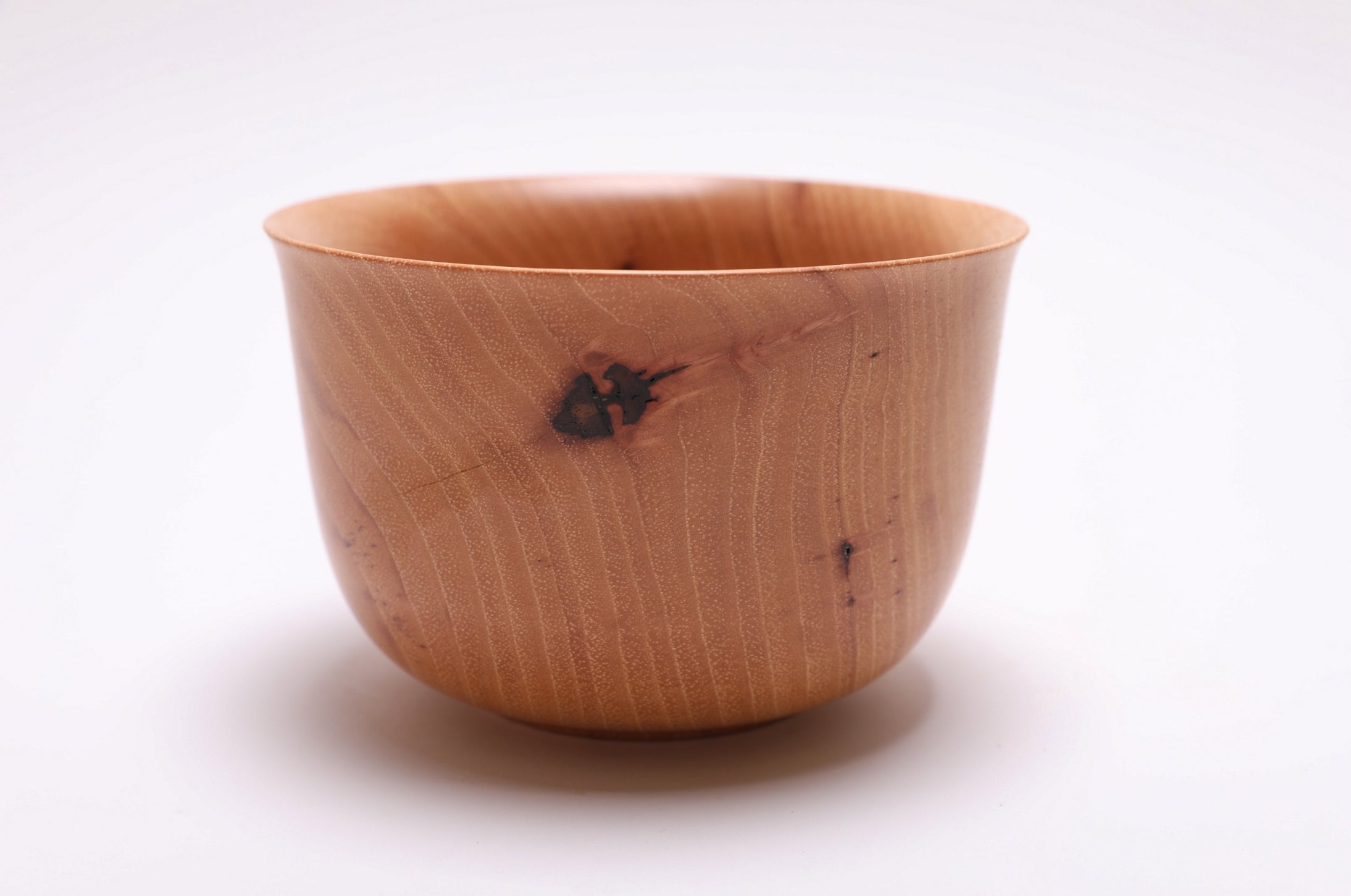 Side view of hand-turned pecan wood bowl with repaired stress crack and natural bud scars
