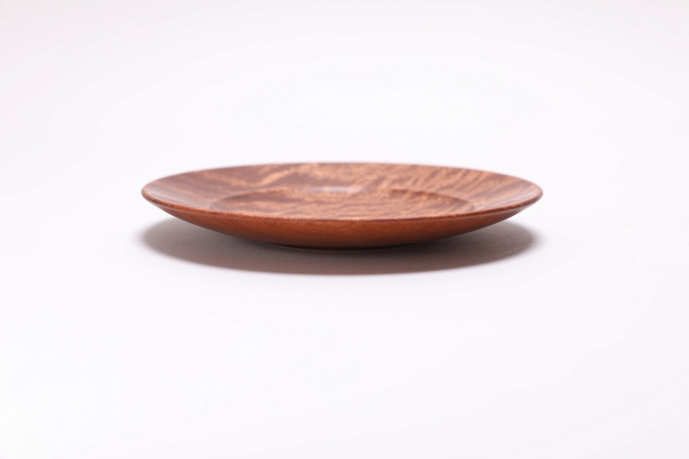 Side view of quilted sapele ring dish showing curved taper, undercut rim, and raised foot profile