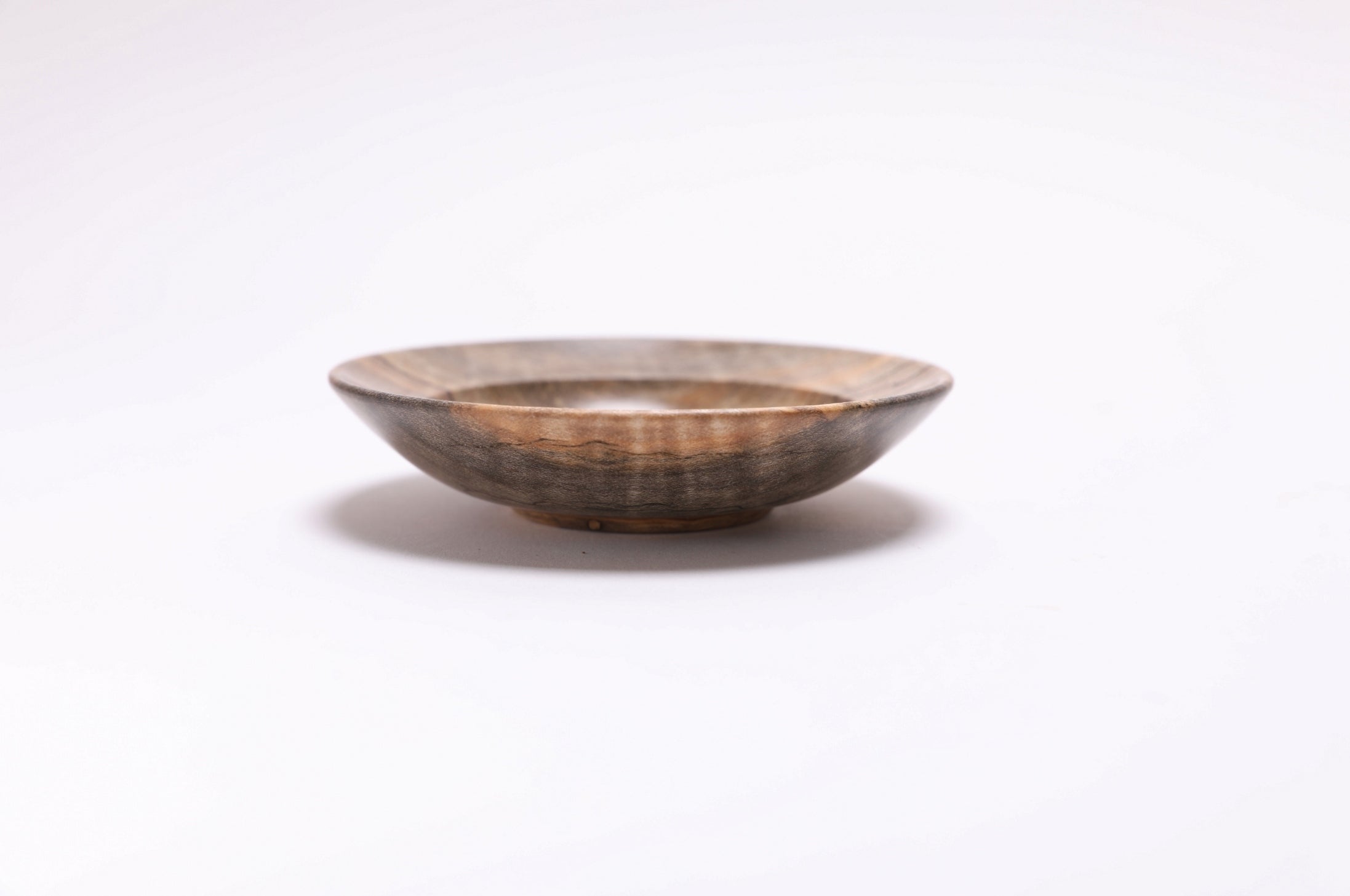 Side view of spalted tiger maple ring dish showing curved taper, undercut rim, and raised foot