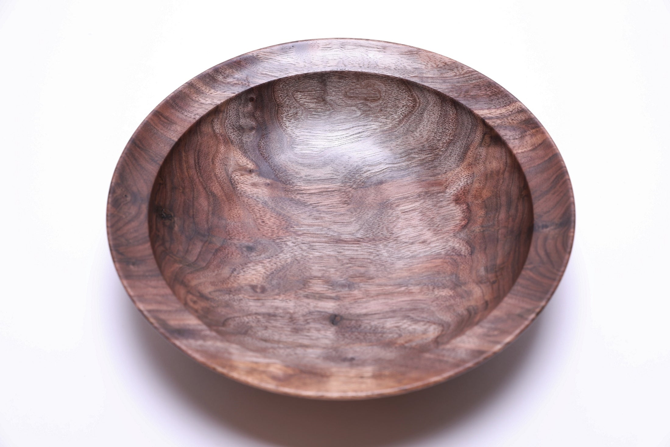 Curly wild black walnut wooden bowl top view rotated 180 degrees — sweeping curly figure with contrasting dark chocolate brown and copper highlights, undercut rim detail visible at edge