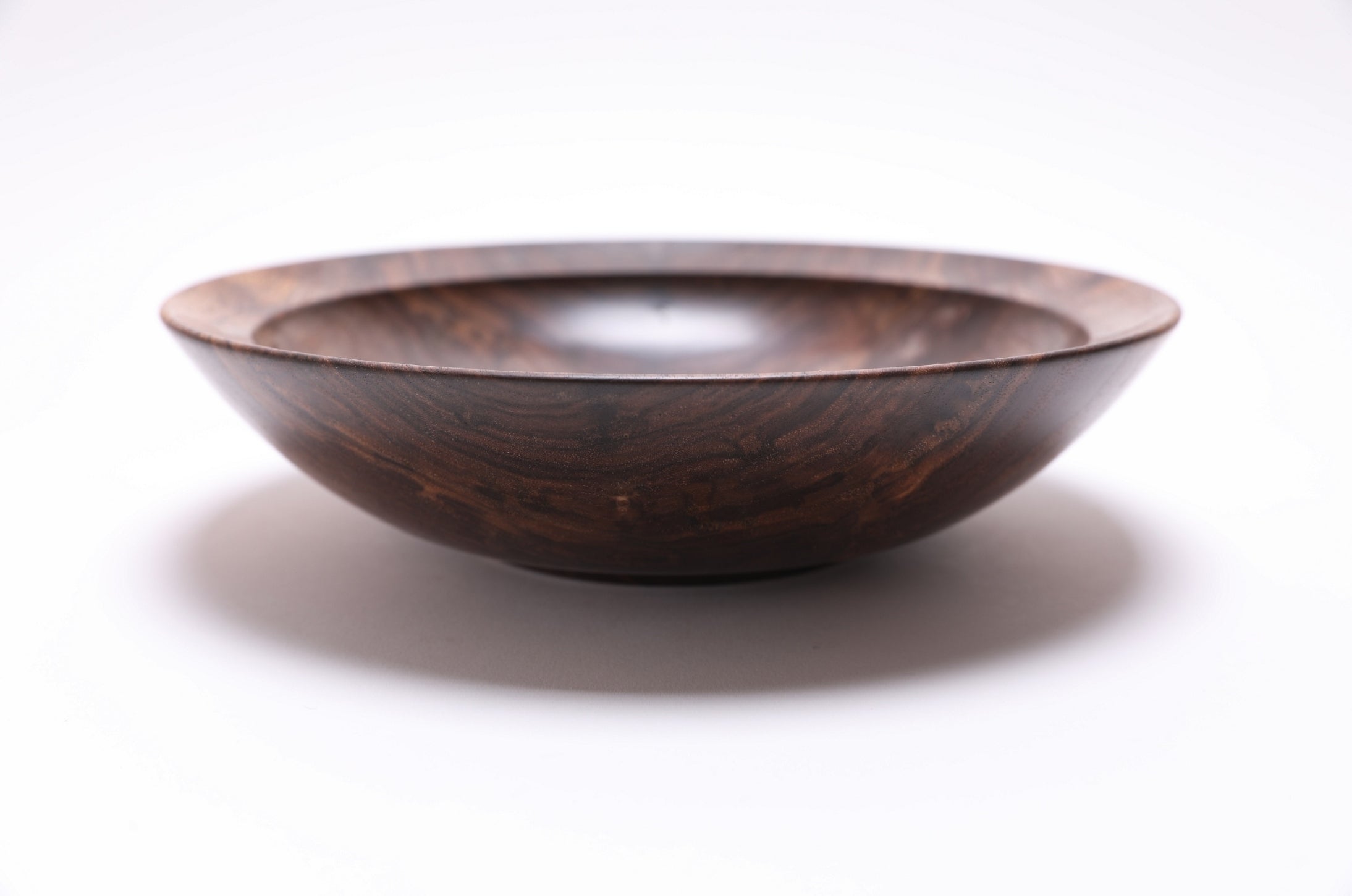  Curly wild black walnut wooden bowl side view — rounded curved taper with undercut rim and raised foot, dark chocolate and copper tones, food-safe oil finish