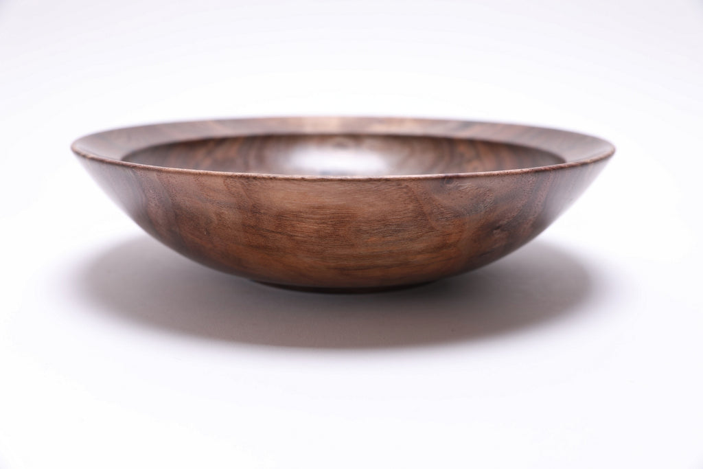 Curly wild black walnut wooden bowl side view rotated 90 degrees — low profile 2.5-inch depth with graceful curved taper, natural curly grain wrapping around the exterior