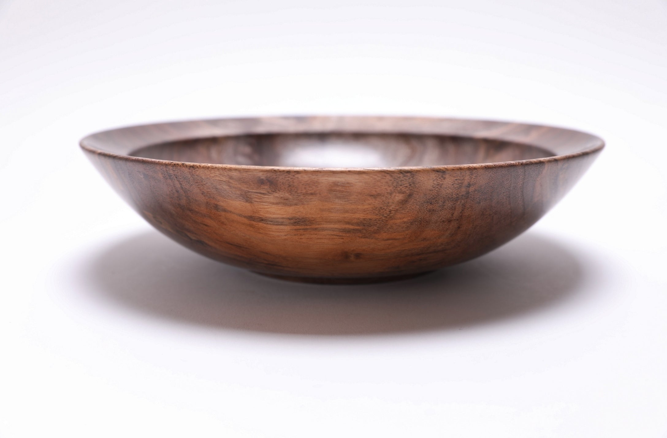 Curly wild black walnut wooden bowl side view rotated 270 degrees — handmade artisan bowl showing full silhouette, undercut rim and curved taper by Sanders Woodworking NC