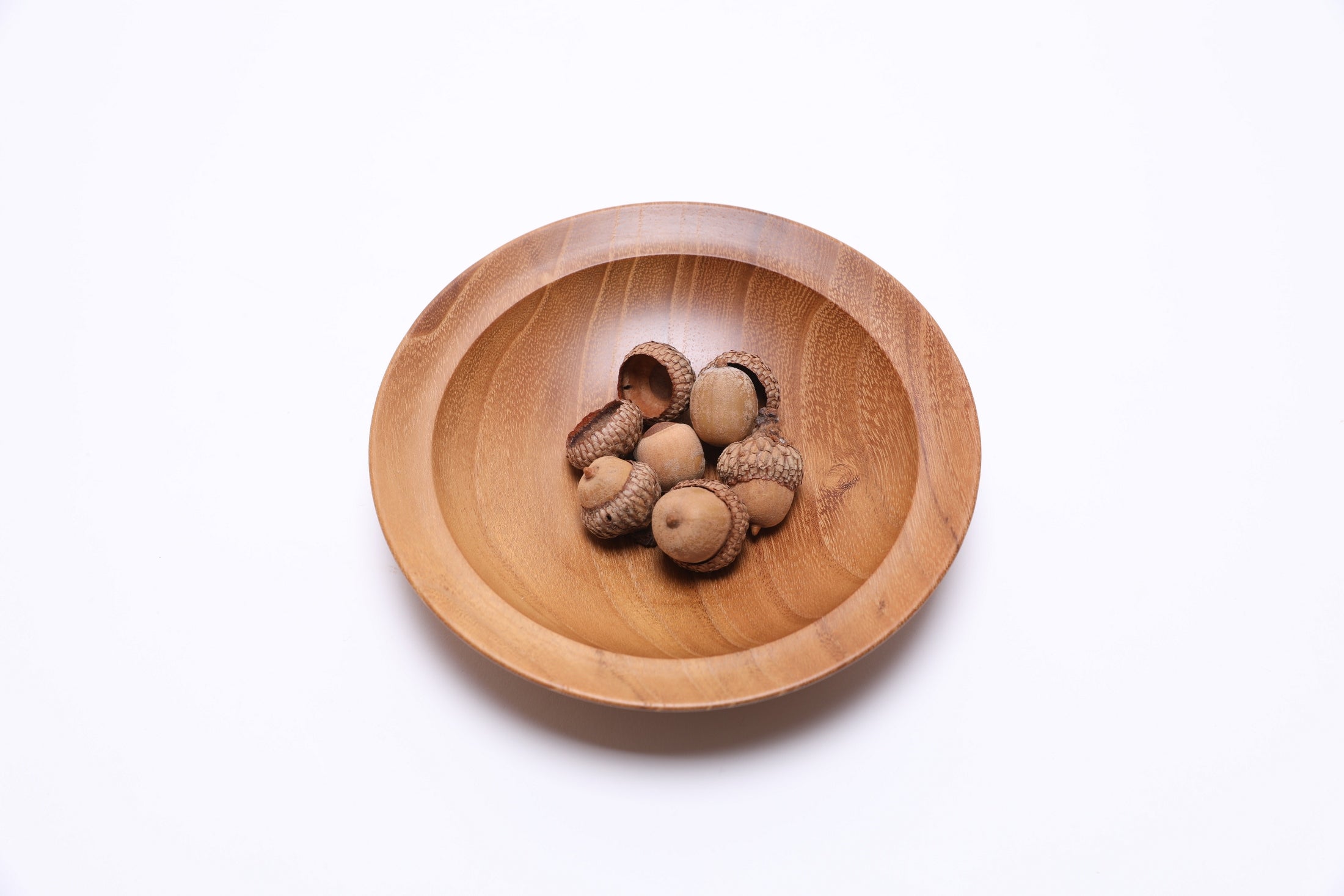 Small black locust wooden bowl top view with acorns for scale, 6 inches wide