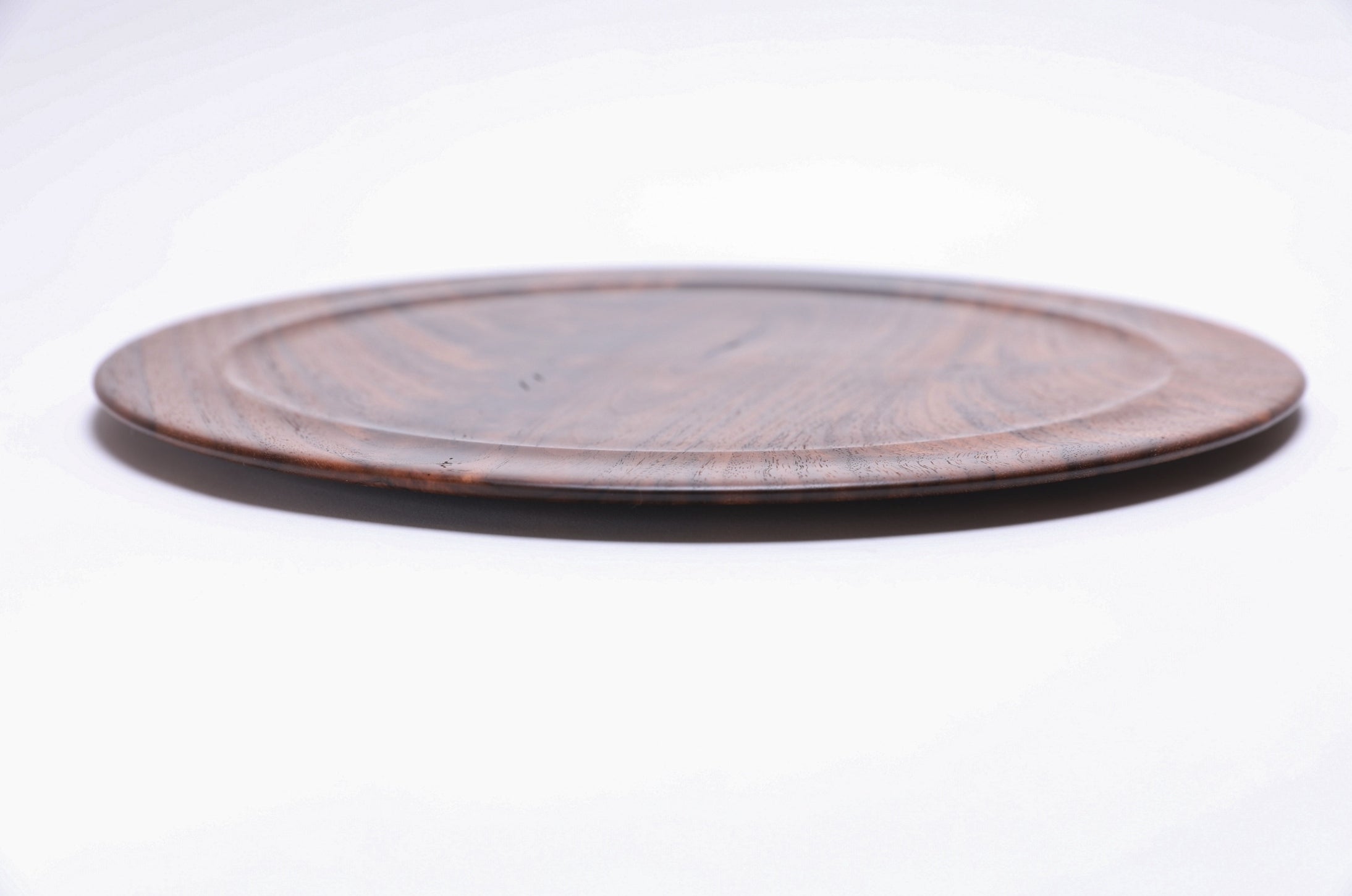 Wild black walnut crotch burl wooden platter, side view showing ½" profile and natural finish