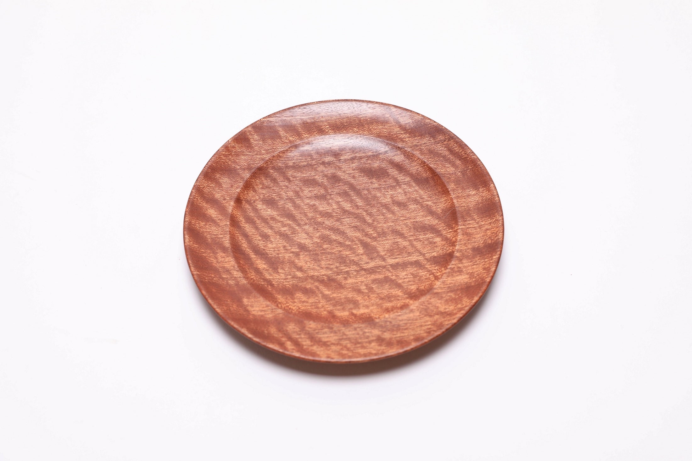 Pommele ribbon sapele wooden ring dish, top view rotated 45°, chatoyant surface with undercut rim visible