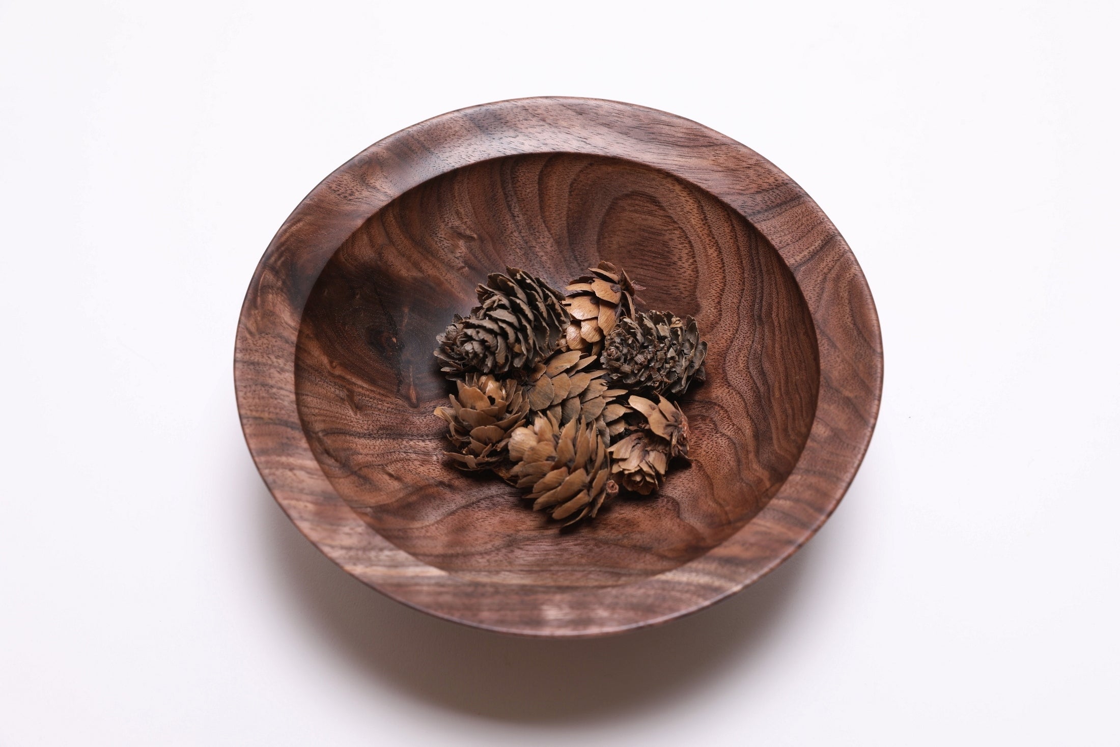 Wild black walnut crotch burl wooden bowl shown with small pinecones for scale — pinecones not included