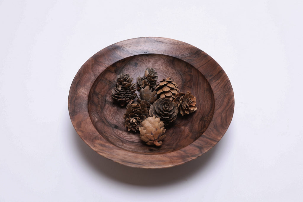 Curly wild black walnut wooden bowl shown with small pinecones for scale — pinecones not included