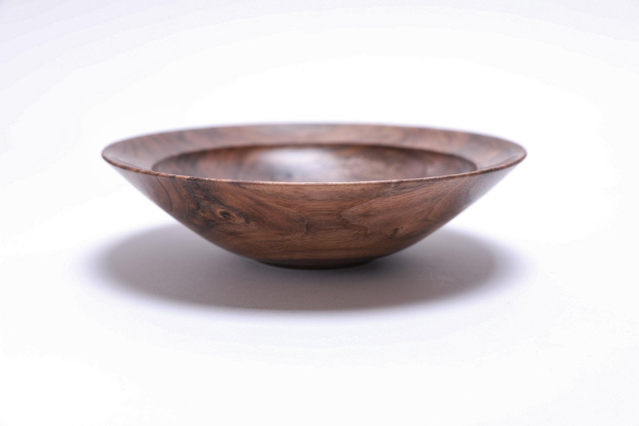 Curly wild black walnut wooden bowl, side view at 270°, raised foot and rich walnut color visible