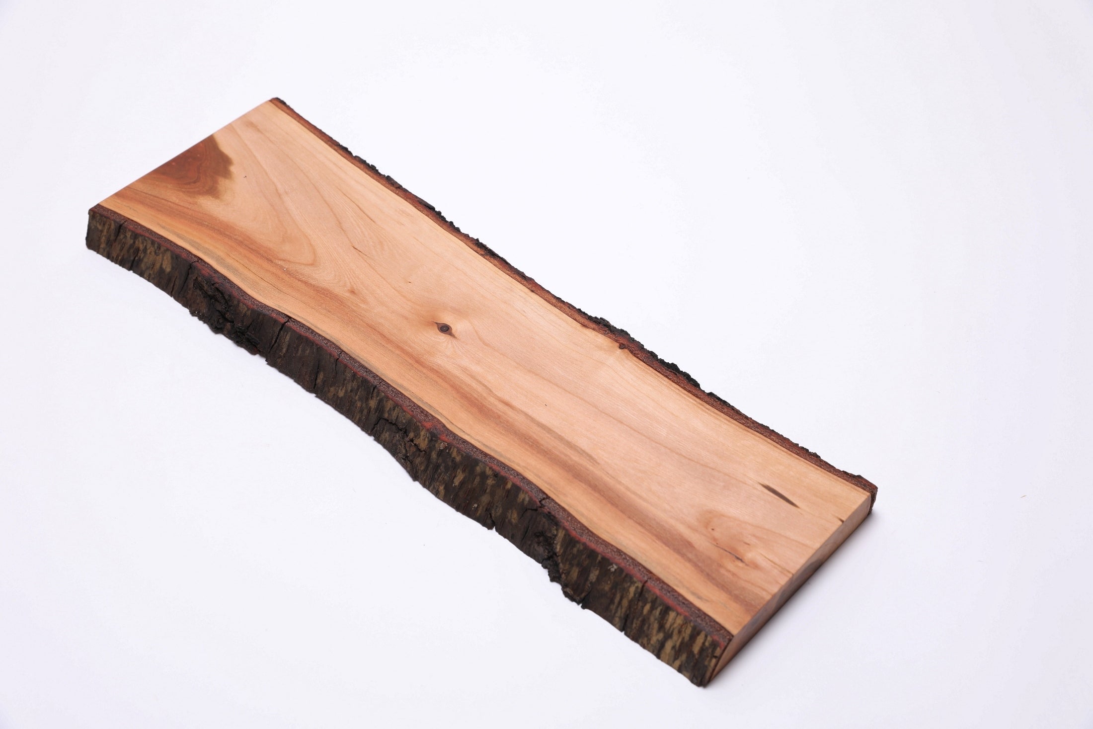 Handcrafted black cherry cheese board with intact bark, overhead view showing wood grain and figure