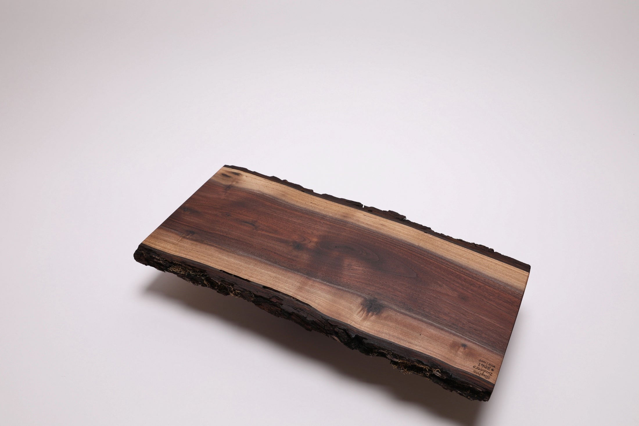 A rectangular live-edge wooden serving board with a natural bark border, displayed on a clean white background.