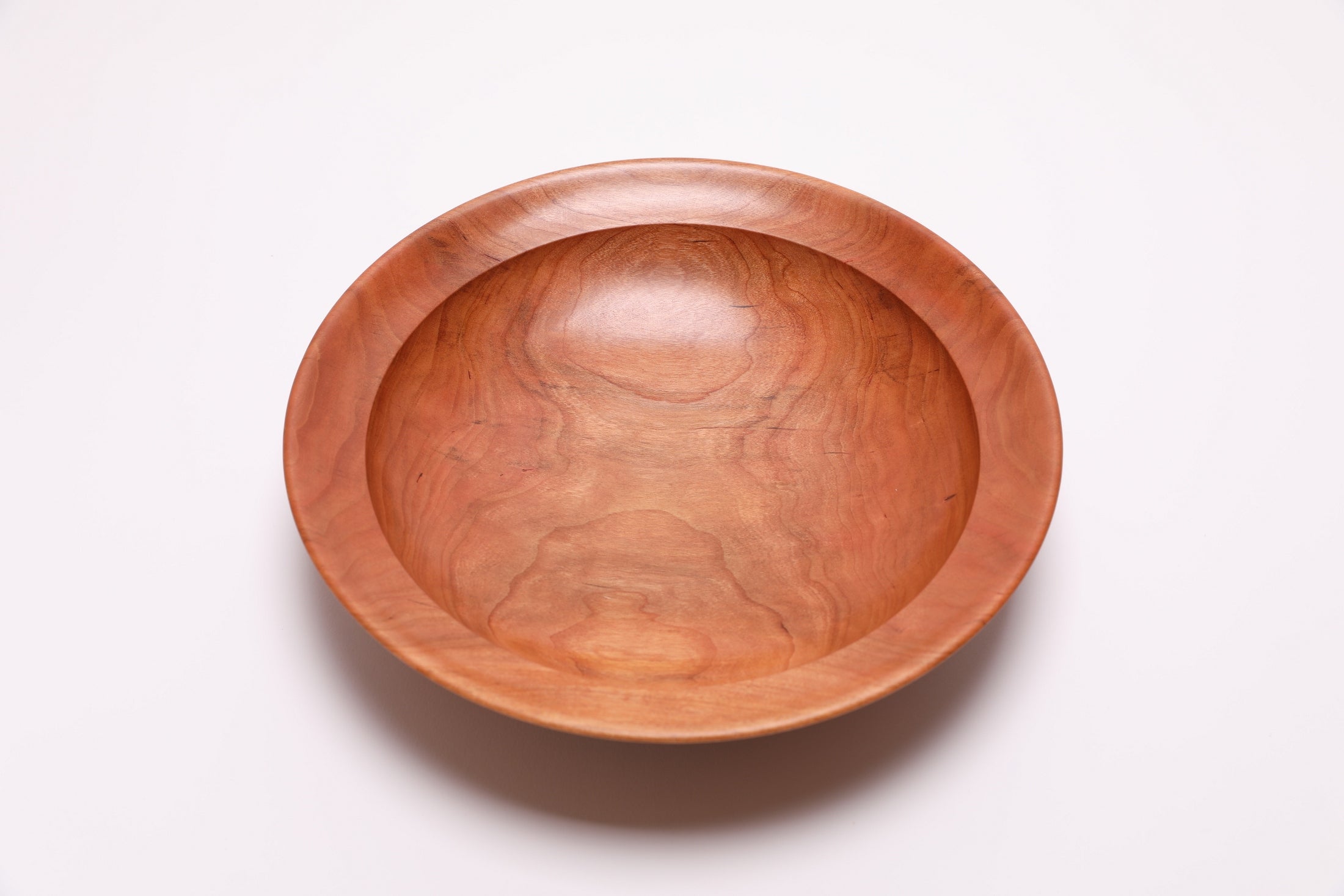 Wild black cherry wooden bowl top view rotated 180°, orange-pink wood tones and amber growth ring detail