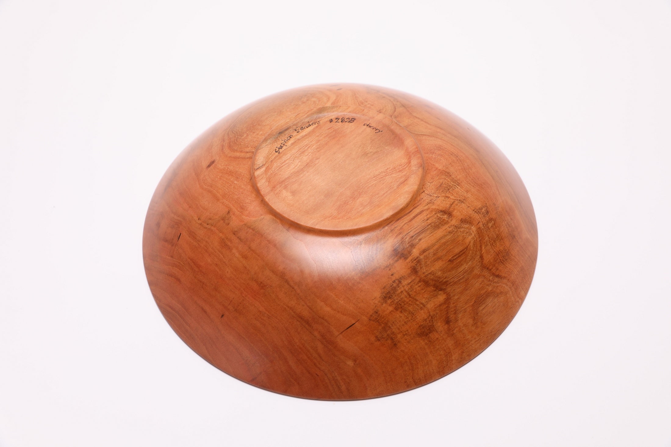 Bottom view of handcrafted wild black cherry wooden bowl showing raised foot and food-safe oil finish
