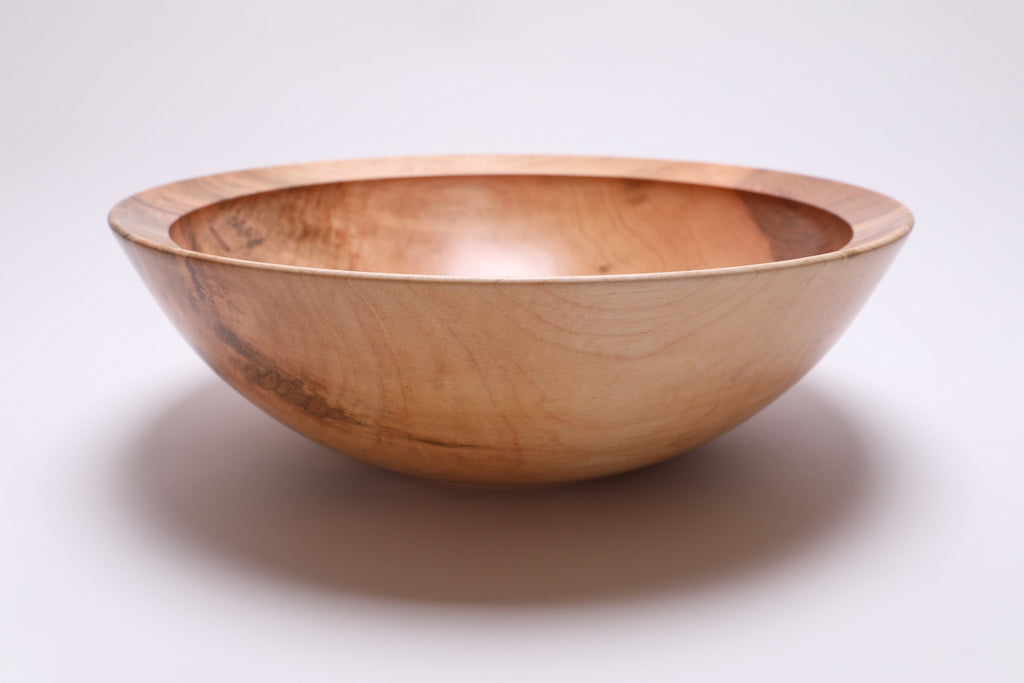 Side view of handcrafted large sugar maple bowl showing curved taper, undercut rim, and raised foot