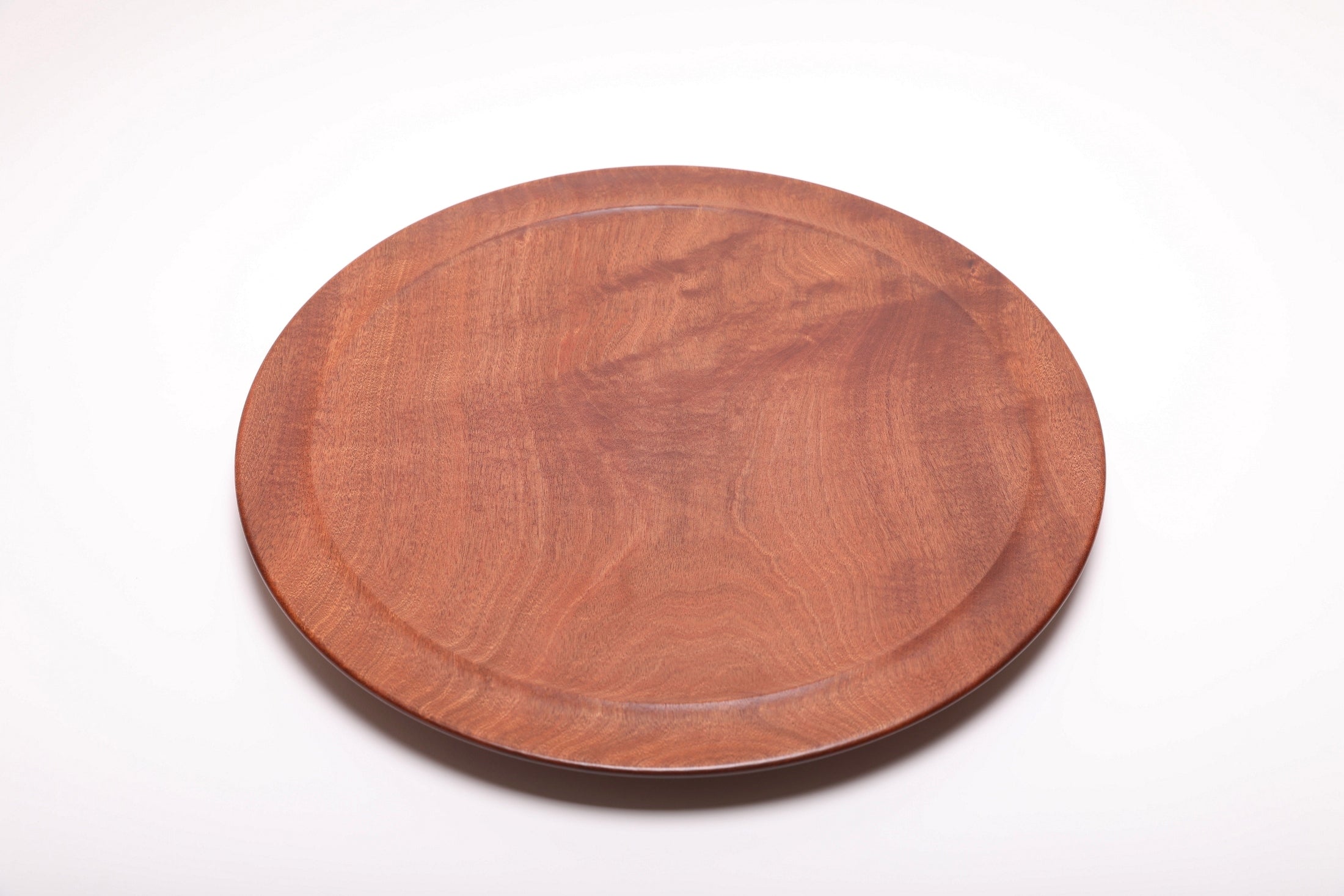 Large Khaya serving platter top view rotated 120°, rich mahogany tones and natural oil finish
