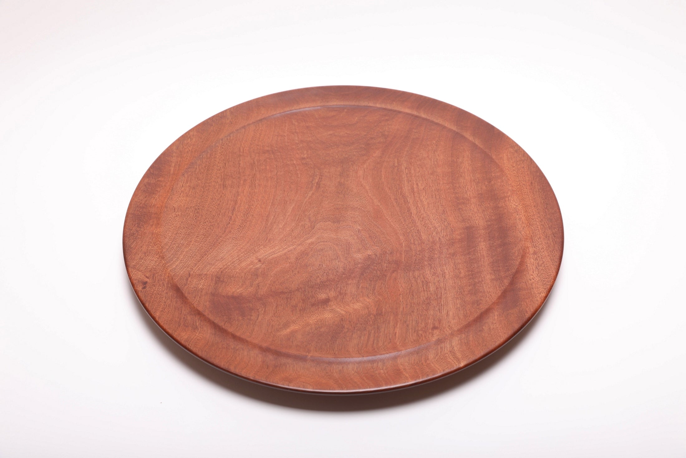 Large Khaya serving platter top view rotated 240°, African mahogany figure and undercut rim detail
