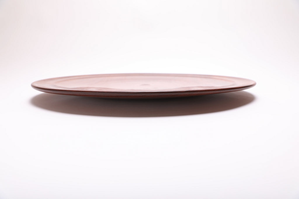 Side view of handcrafted large Khaya serving platter showing curved taper, undercut rim, and raised foot – 1 1/4" depth