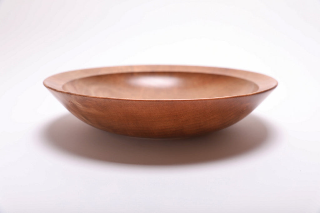 Side view of handcrafted sweet gum wooden bowl showing curved taper, undercut rim, and raised foot