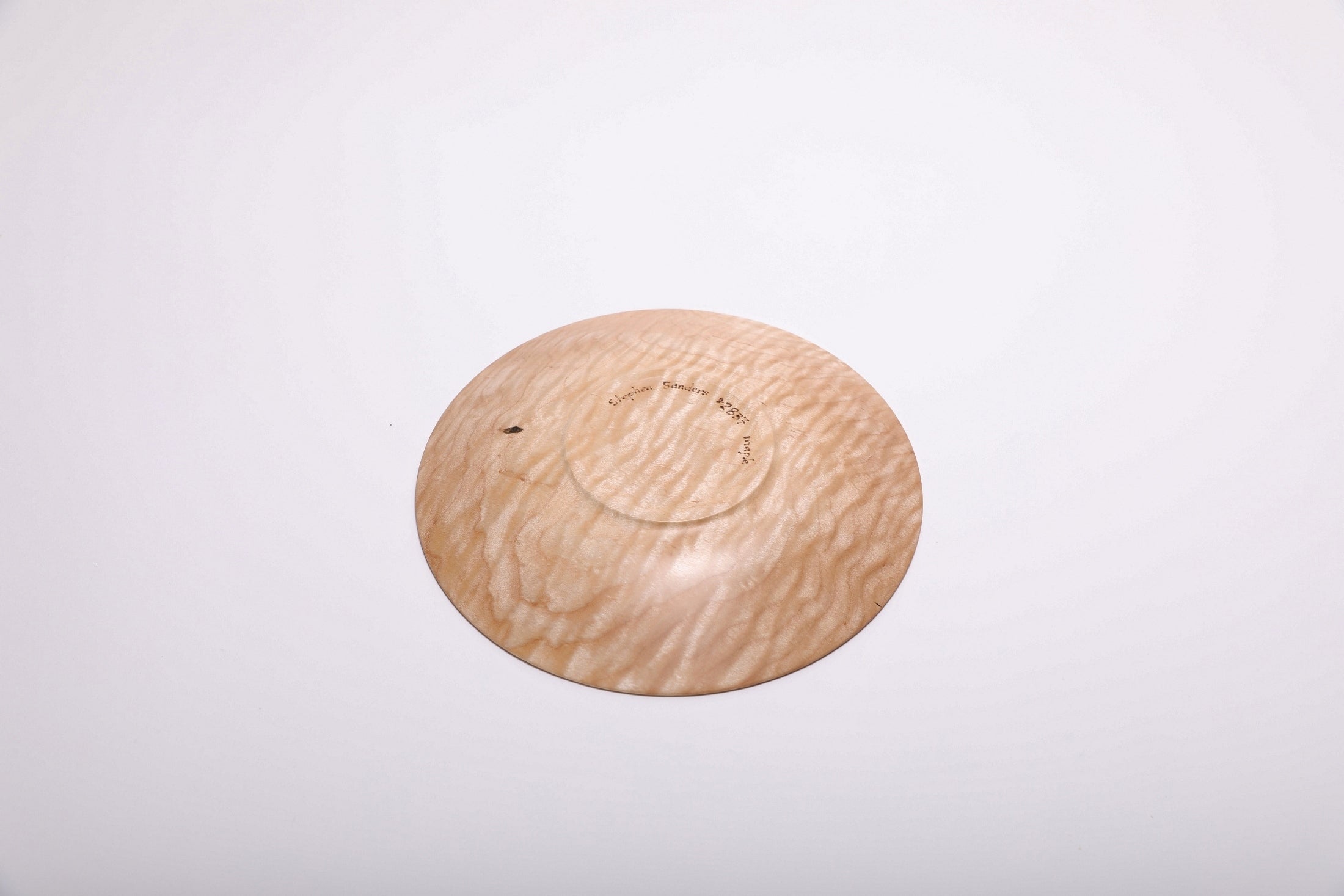 Bottom view of handcrafted curly quilted maple shallow bowl showing raised foot and food-safe oil finish