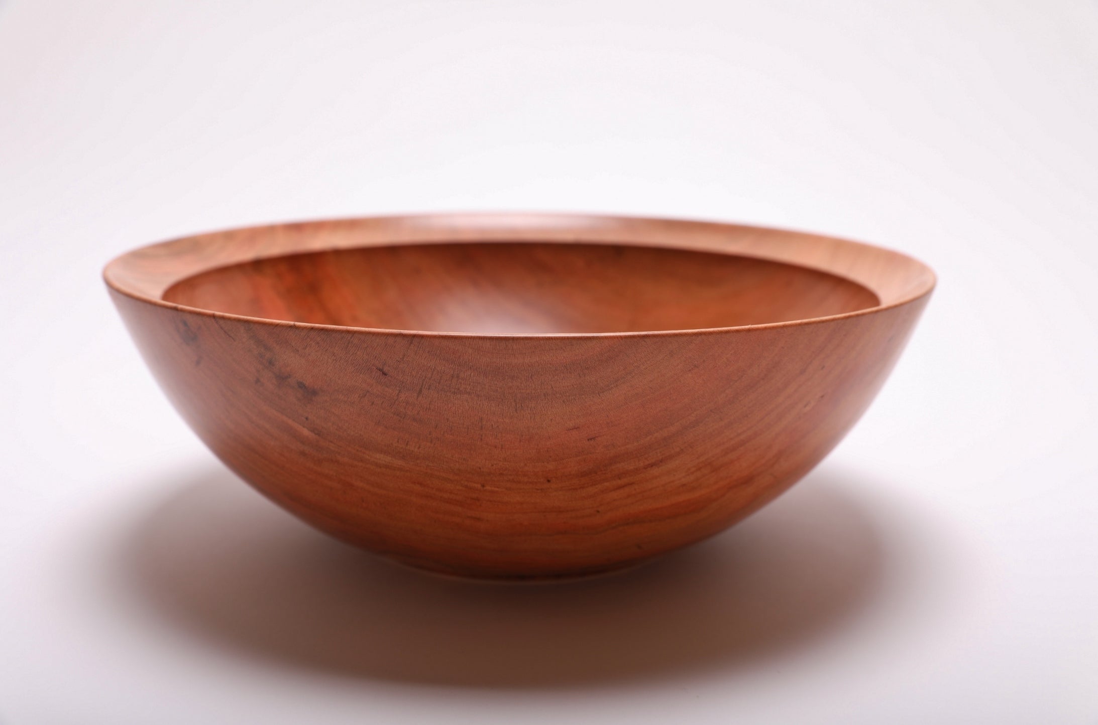 Side view of handcrafted spalted wild black cherry bowl showing curved taper, undercut rim, and raised foot