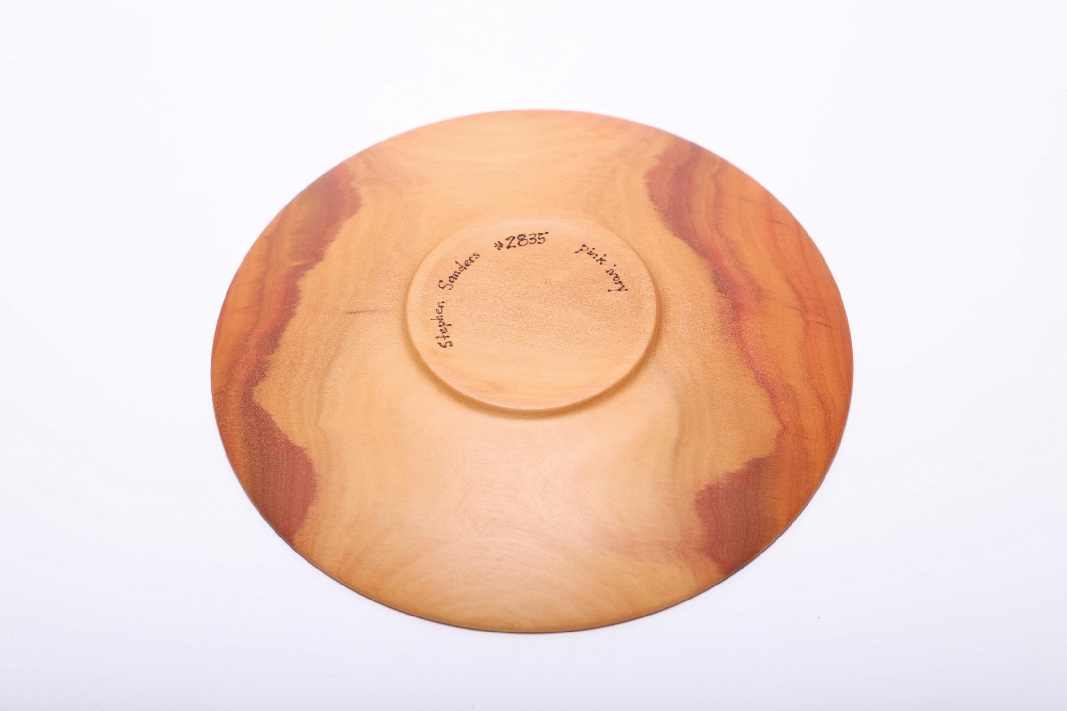 Bottom view of hand-turned pink ivory wood dish showing raised foot and natural oil finish on base