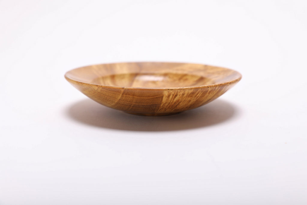 Side view of mulberry burl ring dish showing rounded rim, curved taper, undercut edge, and small raised foot
