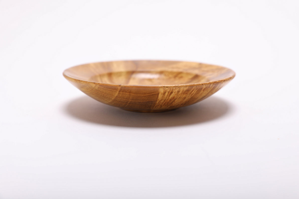 Side view of mulberry burl ring dish showing rounded rim, curved taper, undercut edge, and small raised foot