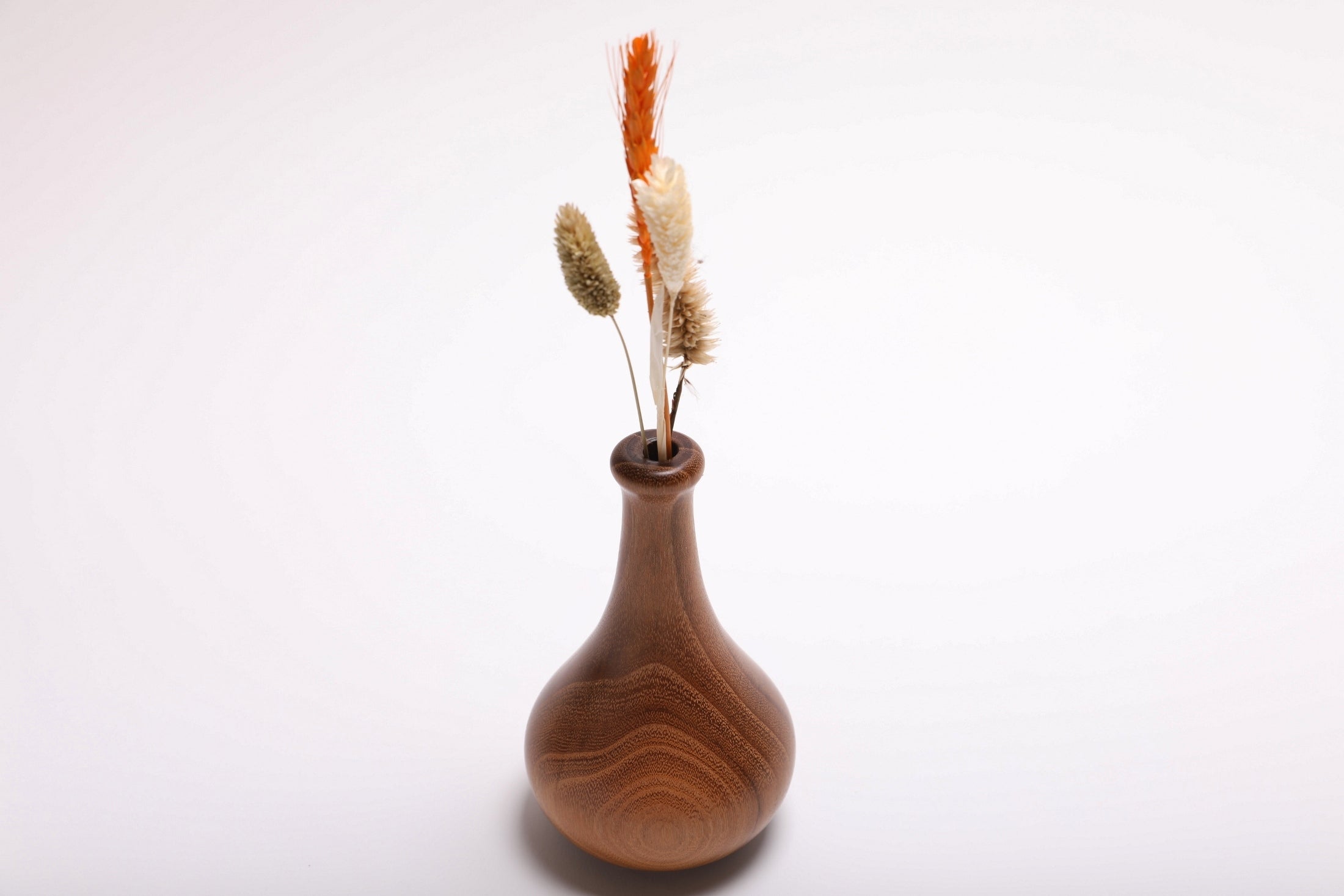 Black locust dry vase with dried flowers rotated 270 degrees showing slender neck detail and natural oil finish
