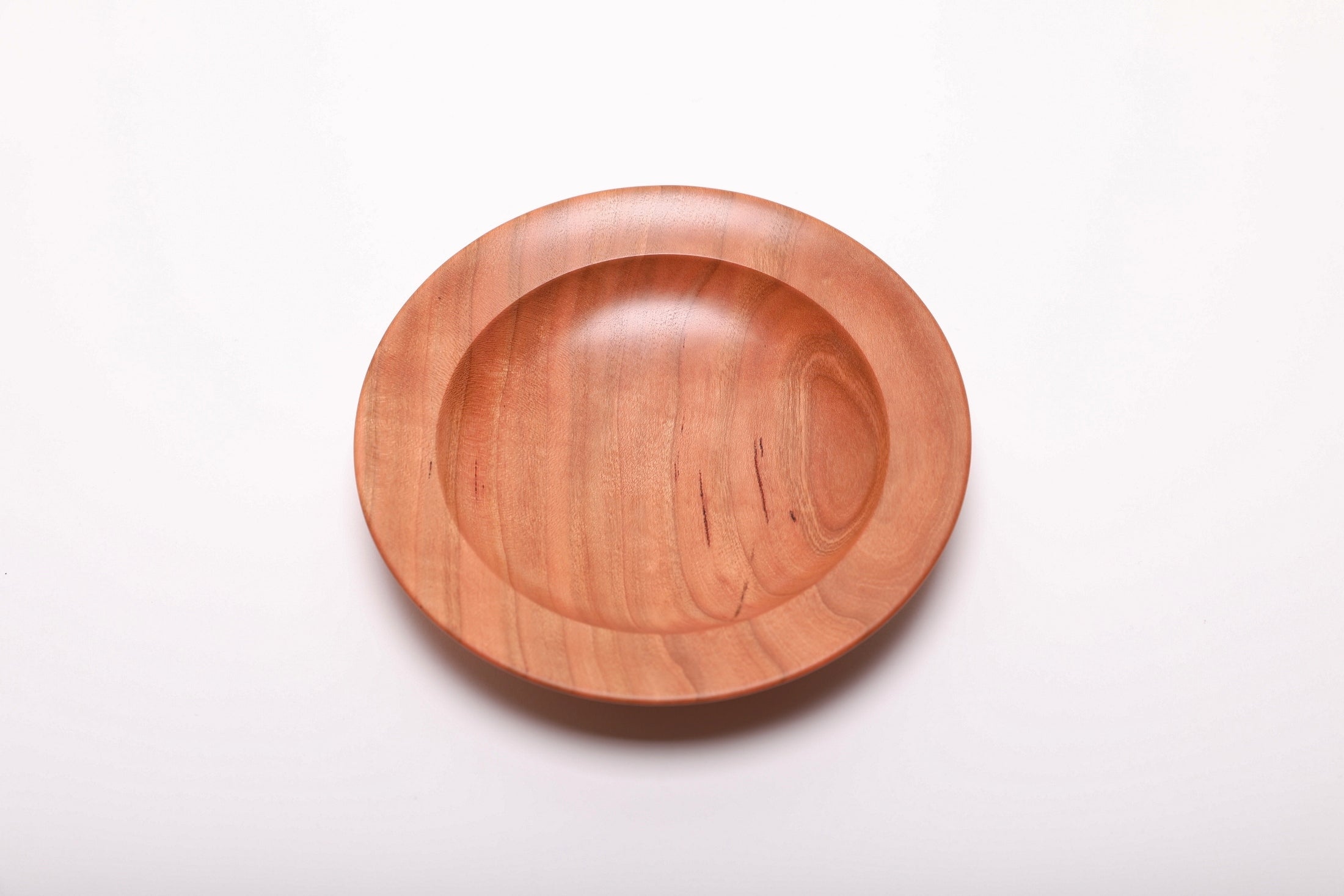 Top-down view of quartersawn cherry wood ring dish rotated 270 degrees displaying copper and pink wood tones with amber grain detail
