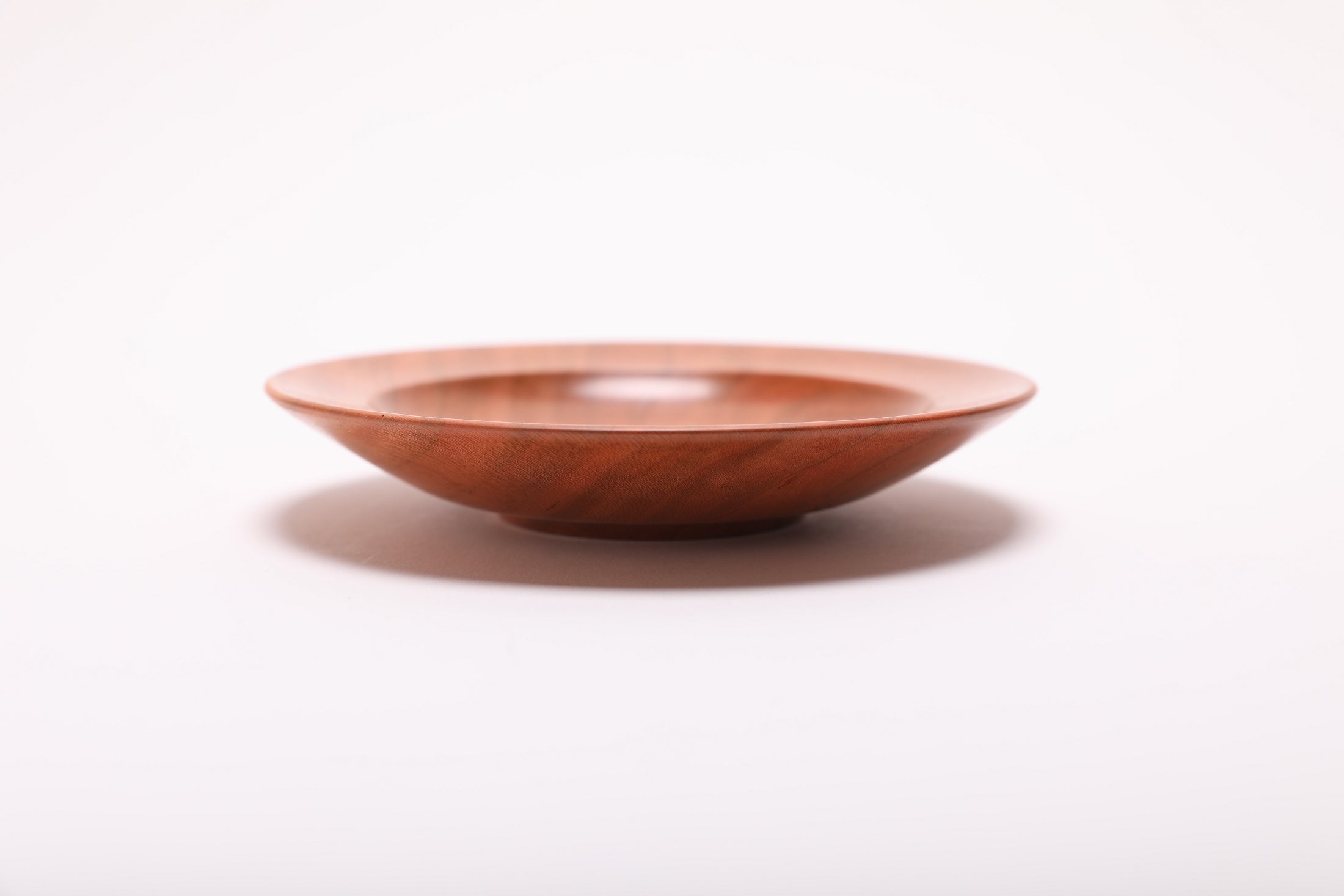 Side profile of hand-turned wild black cherry jewelry dish rotated 90 degrees revealing shallow elegant form and natural oil finish