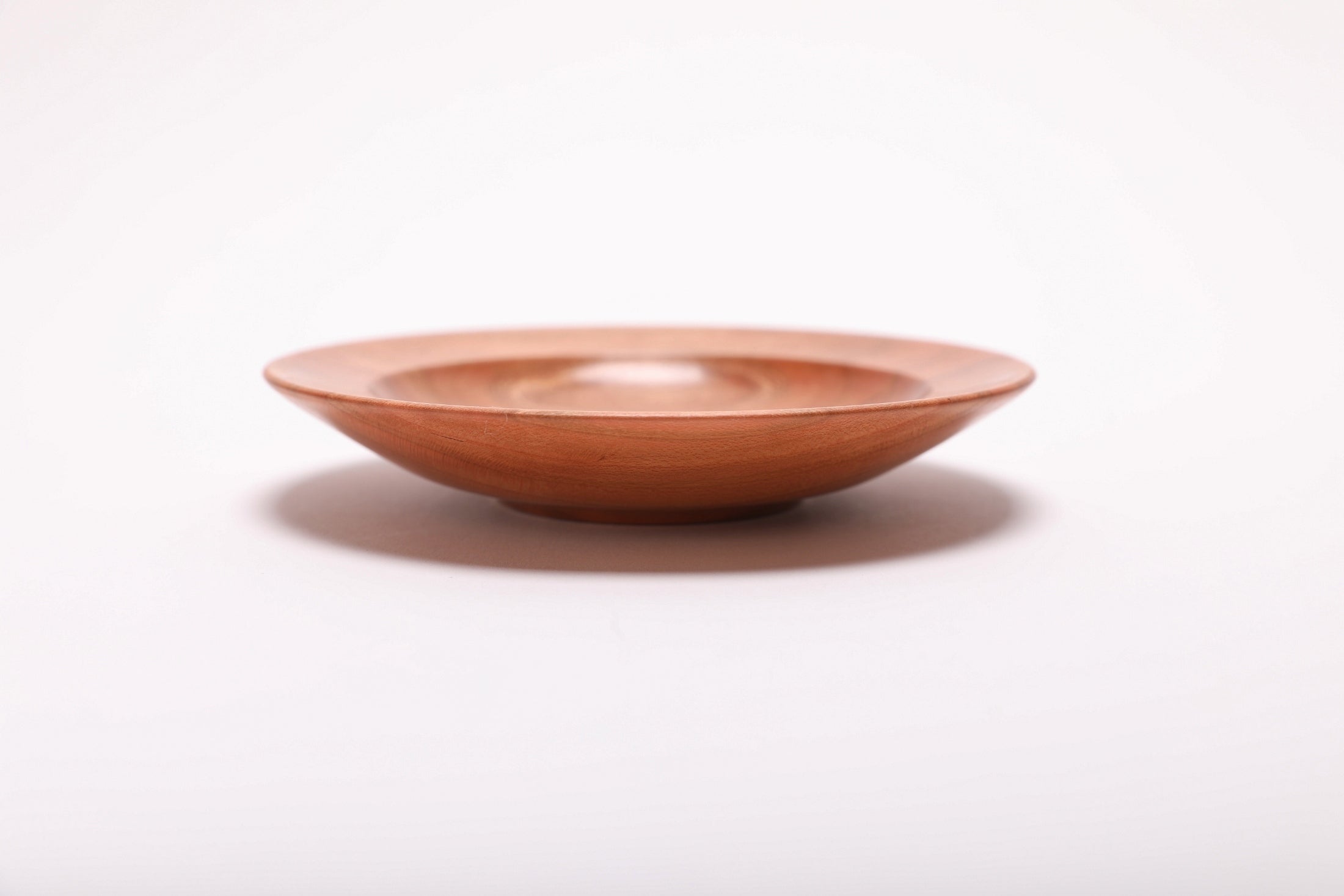 Side view of quartersawn cherry wood ring dish rotated 180 degrees showing exterior grain and warm copper coloration