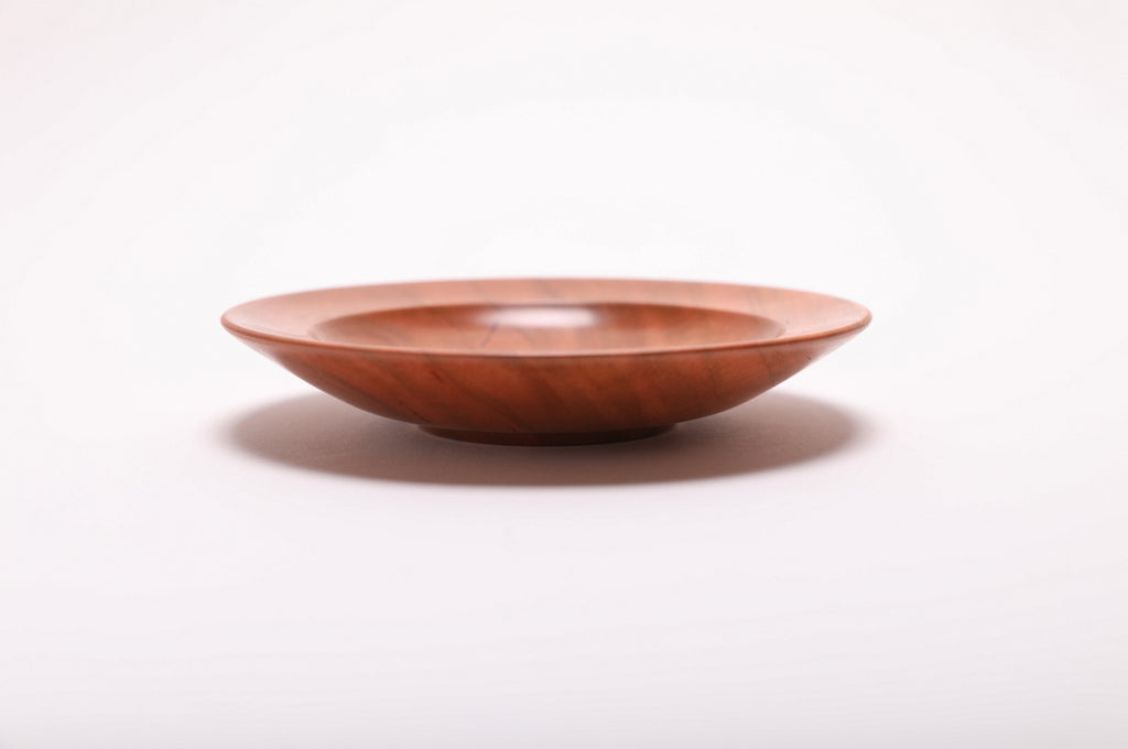 Side angle of wild black cherry ring dish rotated 270 degrees highlighting raised foot detail and smooth curved taper