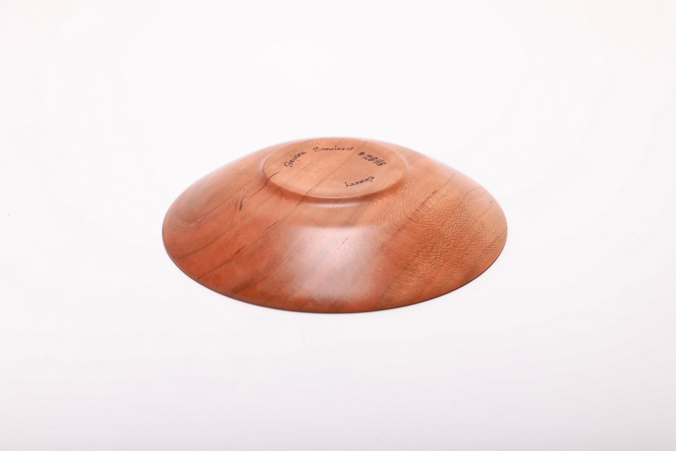 Bottom view of hand-turned quartersawn wild black cherry ring dish showing raised foot and natural oil finish on base