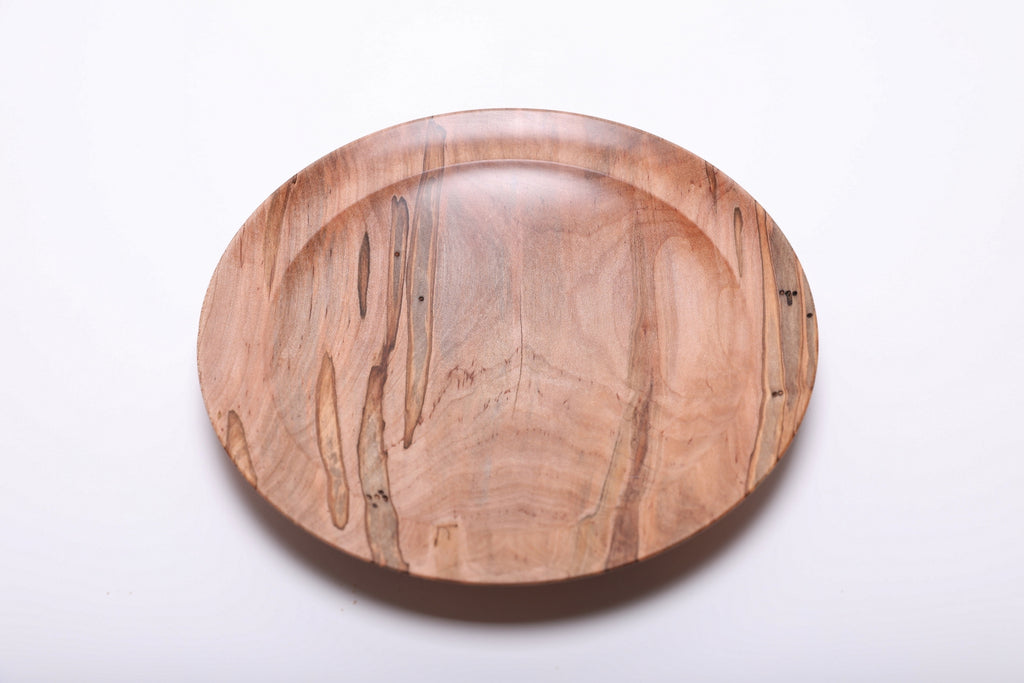 Top-down view of ambrosia maple shallow plate rotated 270 degrees displaying beetle hole pattern and fungus-colored wood grain