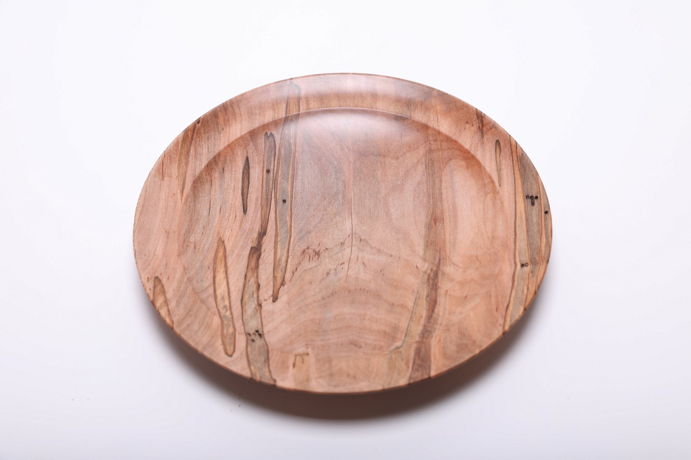 Top-down view of ambrosia maple shallow plate rotated 270 degrees displaying beetle hole pattern and fungus-colored wood grain