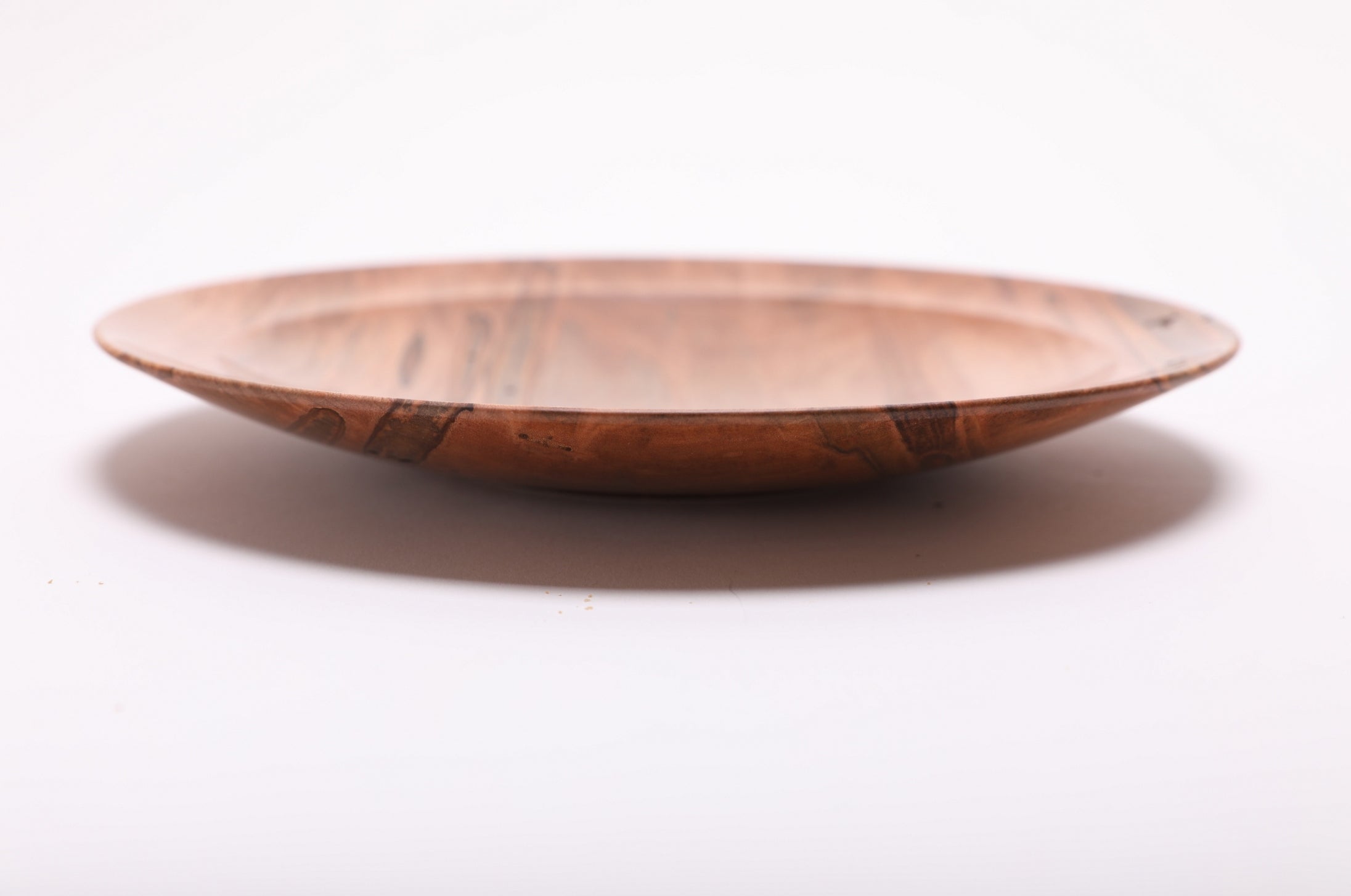 Side view of ambrosia maple shallow dish showing rolled rim, curved taper, undercut edge, and raised foot, handmade in NC USA